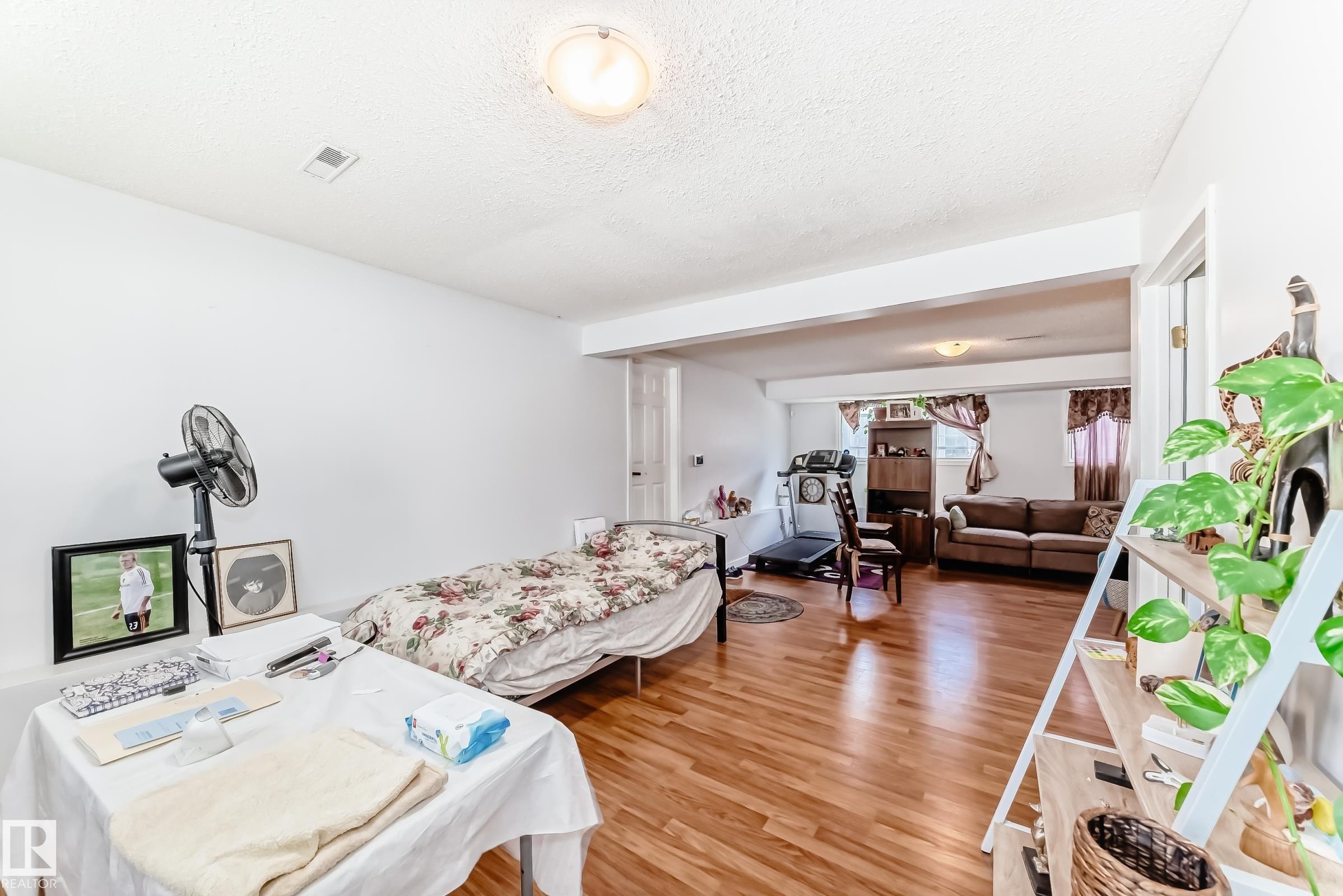 Wood-finish flooring throughout a versatile room with white walls - 1804 51 Street Nw, Edmonton, AB - Indoor Photo Showing Bedroom