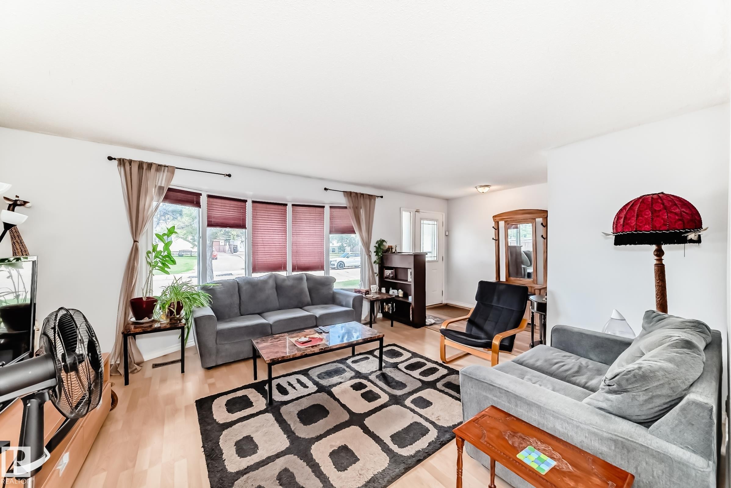 Bright main living area featuring light wood-finish flooring, a bay window with blinds, and white painted walls - 1804 51 Street Nw, Edmonton, AB - Indoor Photo Showing Living Room