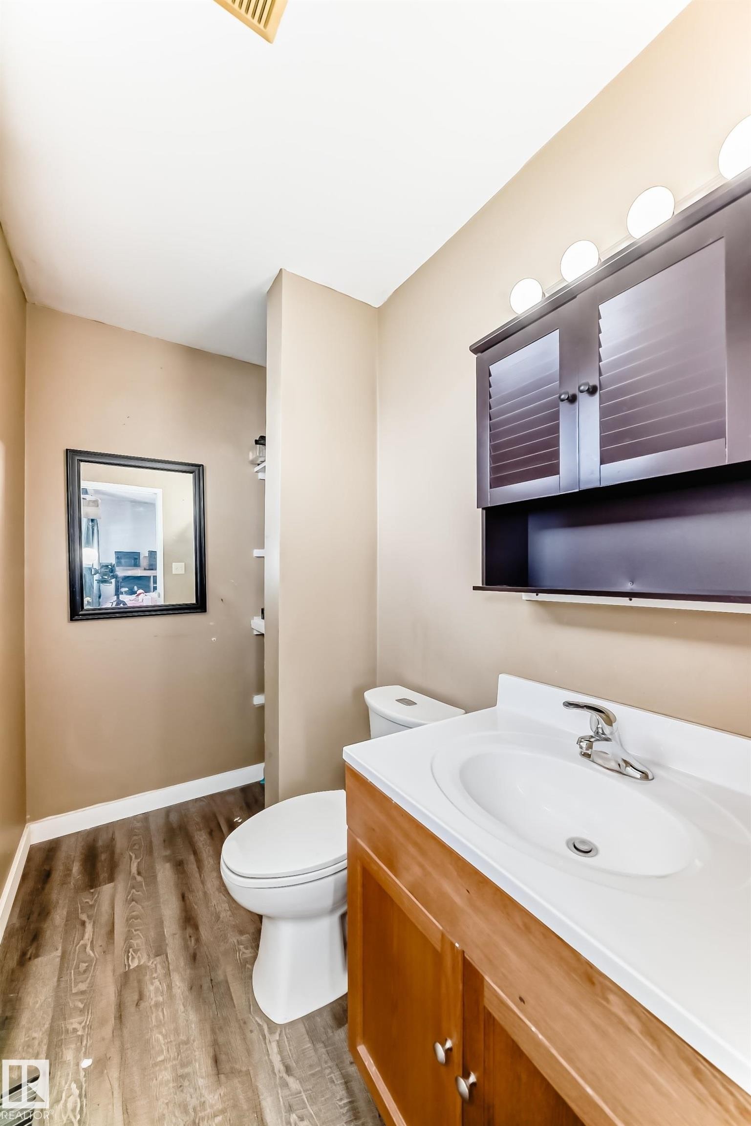 Bathroom featuring a wood-finish vanity with an integrated sink, white toilet, and dark wood-finish wall cabinet - 1804 51 Street Nw, Edmonton, AB - Indoor Photo Showing Bathroom