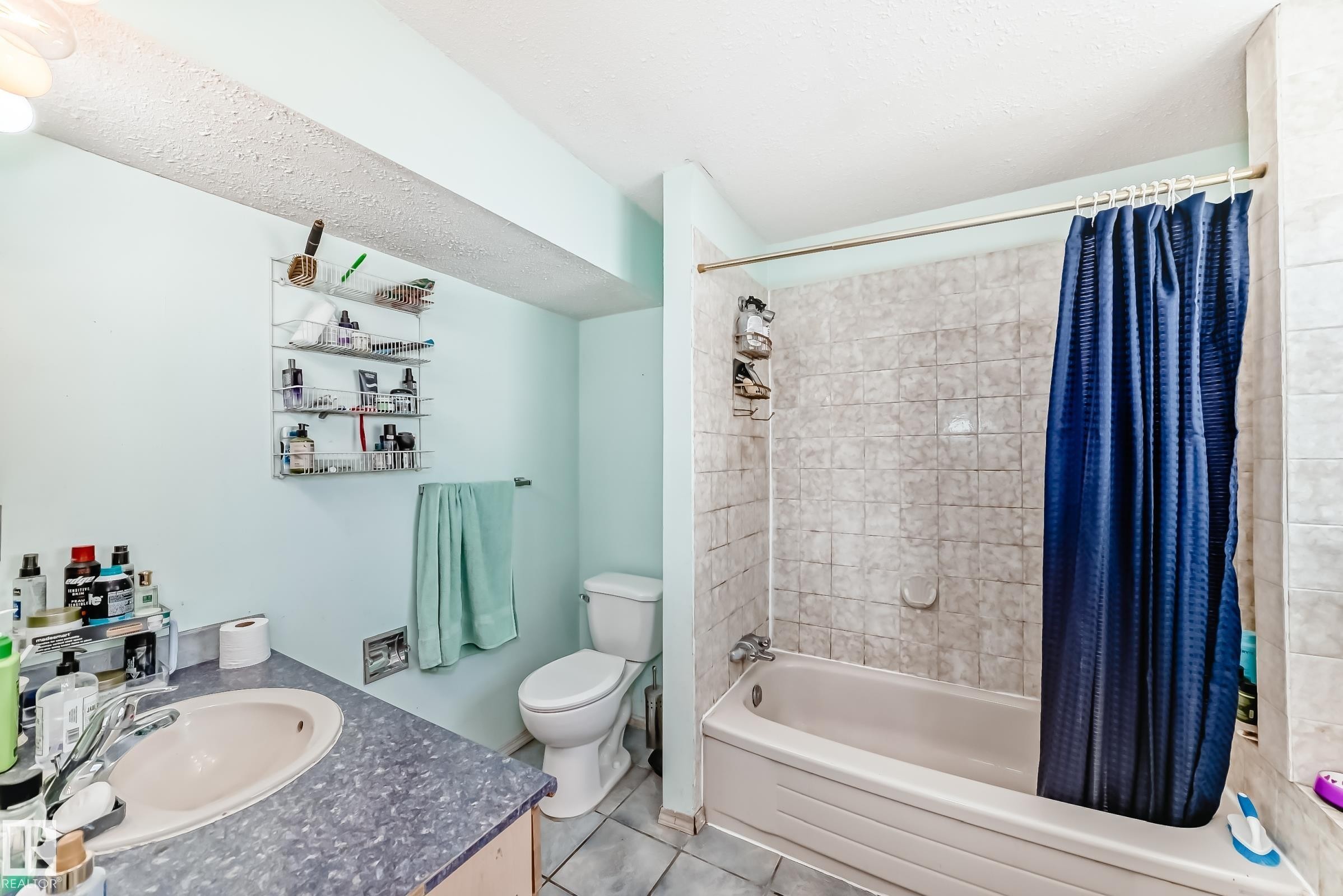 Bathroom featuring a white bathtub, ceramic tile shower surround, and a vanity with a drop-in sink and laminate countertop - 1804 51 Street Nw, Edmonton, AB - Indoor Photo Showing Bathroom