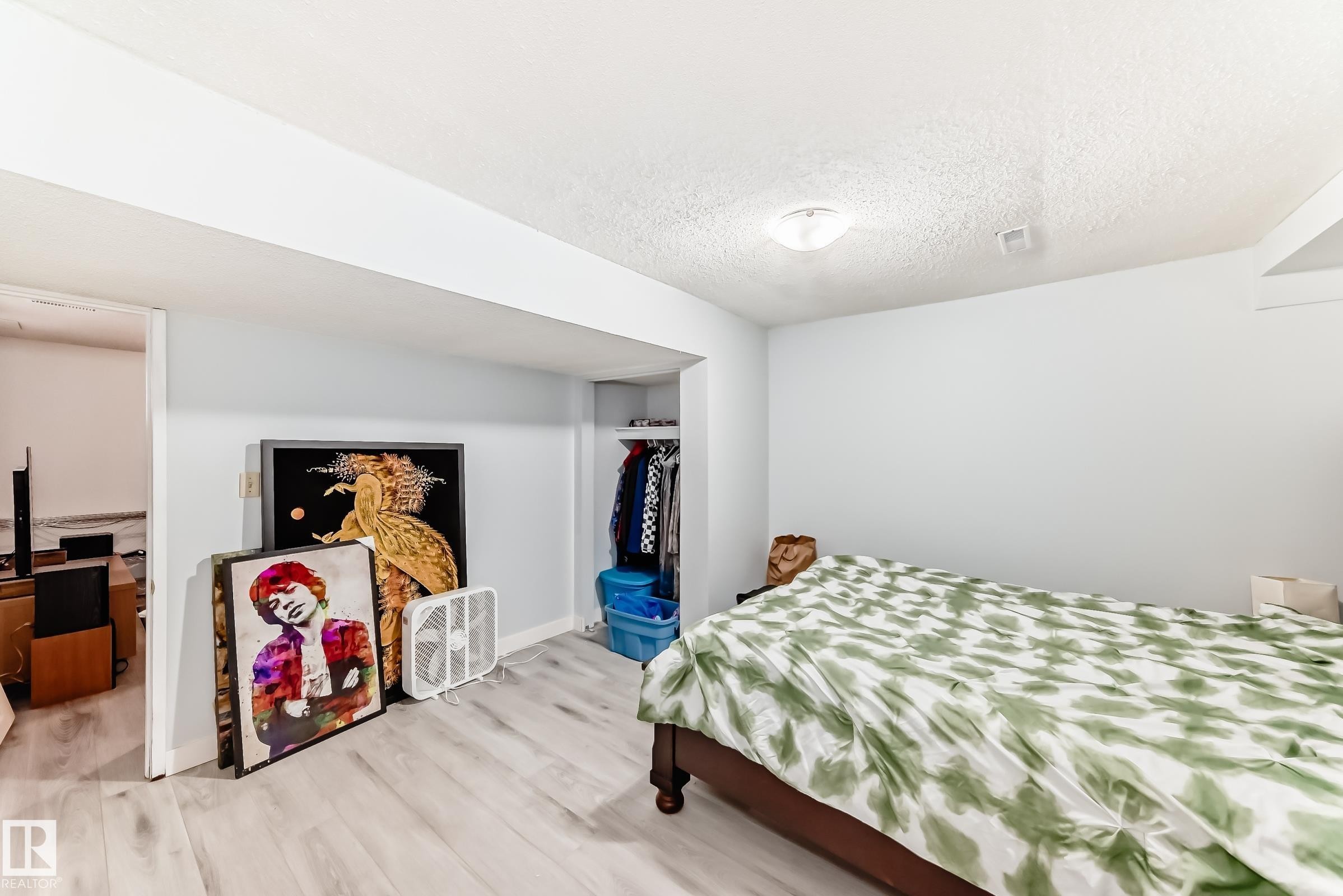 Spacious room featuring wood-finish flooring, light blue wall paint, a built-in recessed closet, and a flush-mount ceiling light fixture - 1804 51 Street Nw, Edmonton, AB - Indoor Photo Showing Bedroom