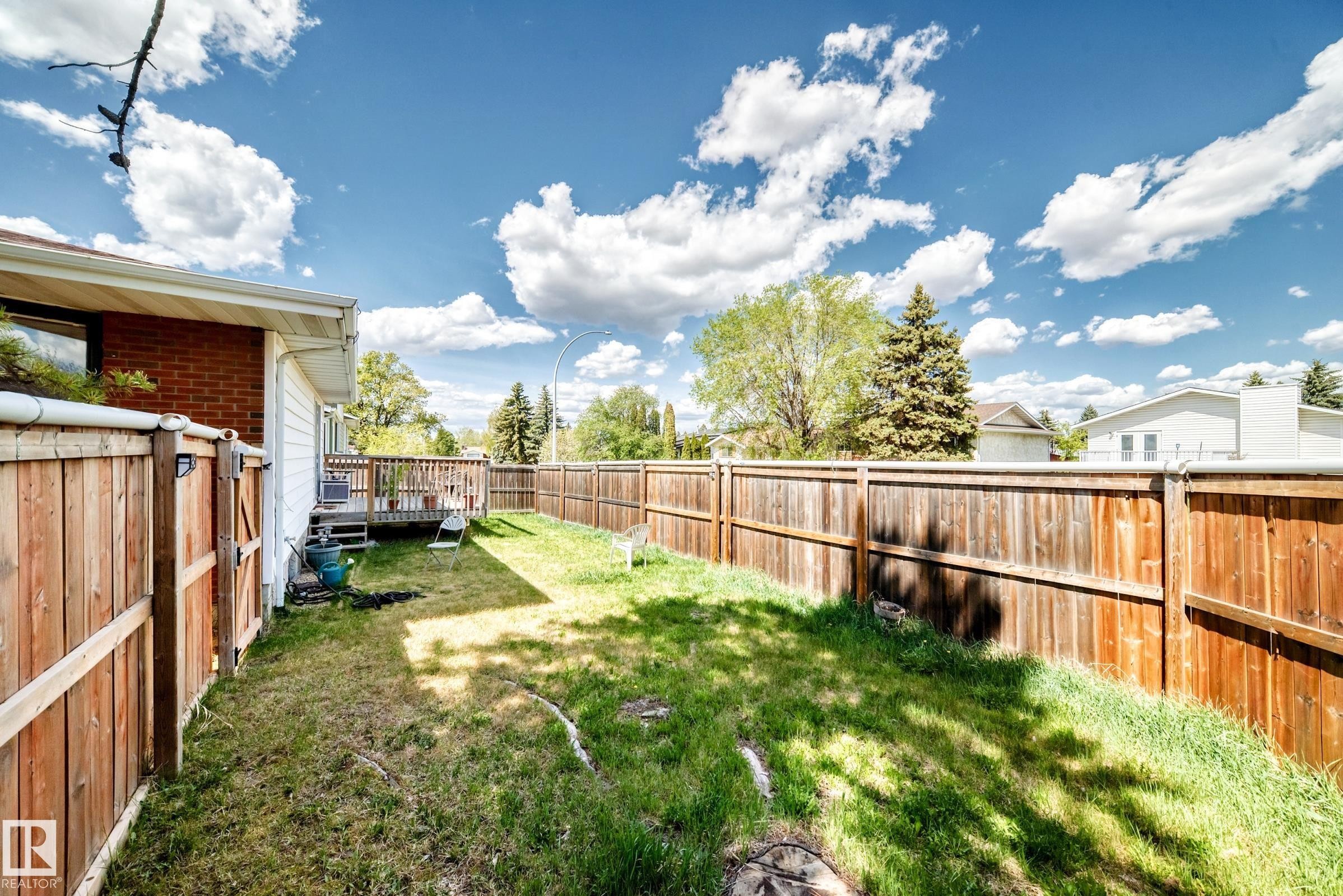 Expansive backyard featuring a wood privacy fence, a wood deck, and a grass lawn - 1804 51 Street Nw, Edmonton, AB - Outdoor