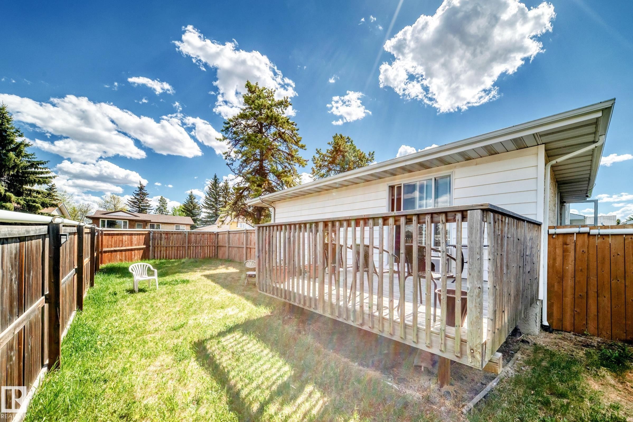 Private backyard featuring a wooden deck with railing, surrounded by a wooden fence, and a manicured lawn - 1804 51 Street Nw, Edmonton, AB - Outdoor