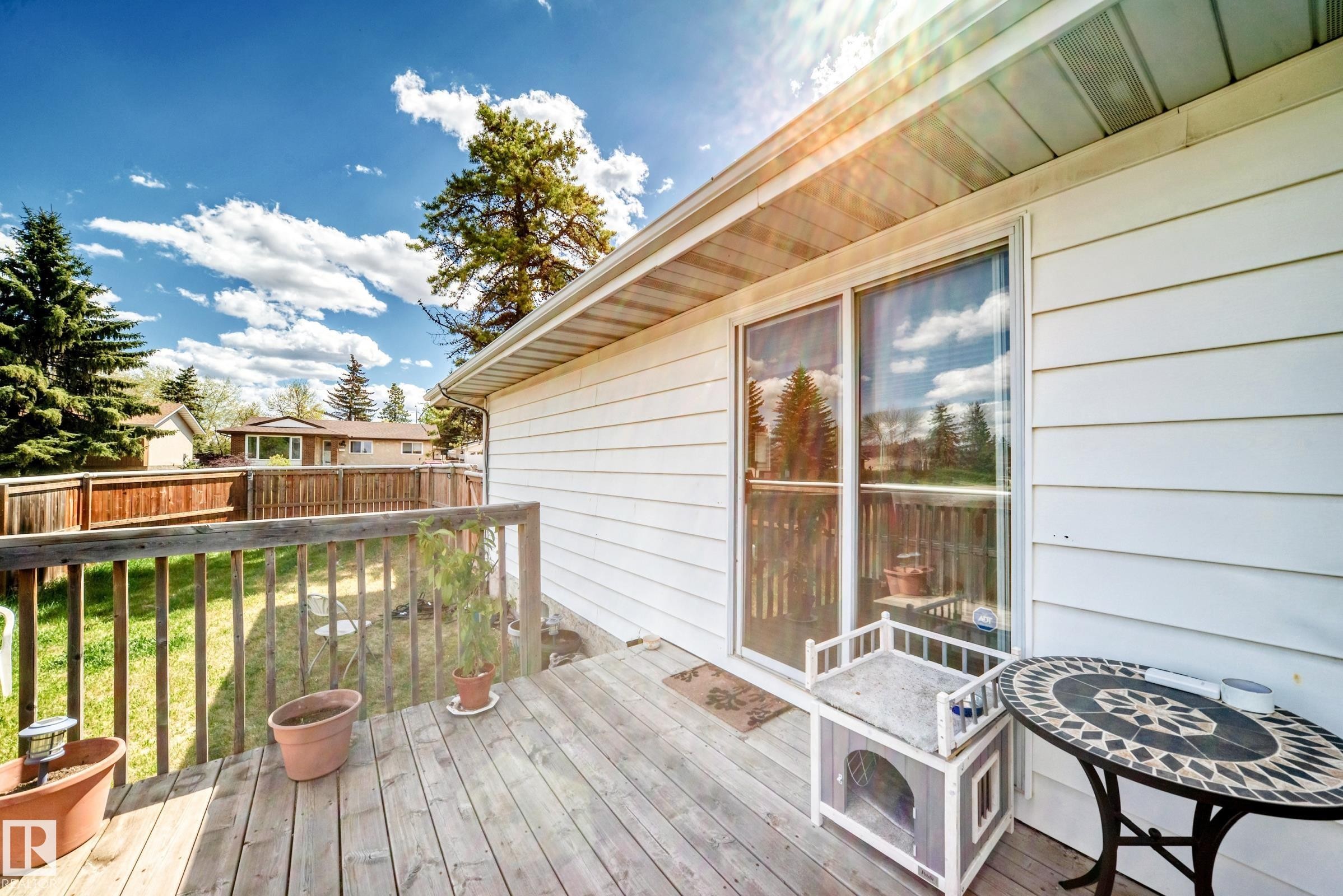 Outdoor wood deck featuring a wooden railing, white siding exterior, and sliding glass patio doors - 1804 51 Street Nw, Edmonton, AB - Outdoor With Deck Patio Veranda With Exterior