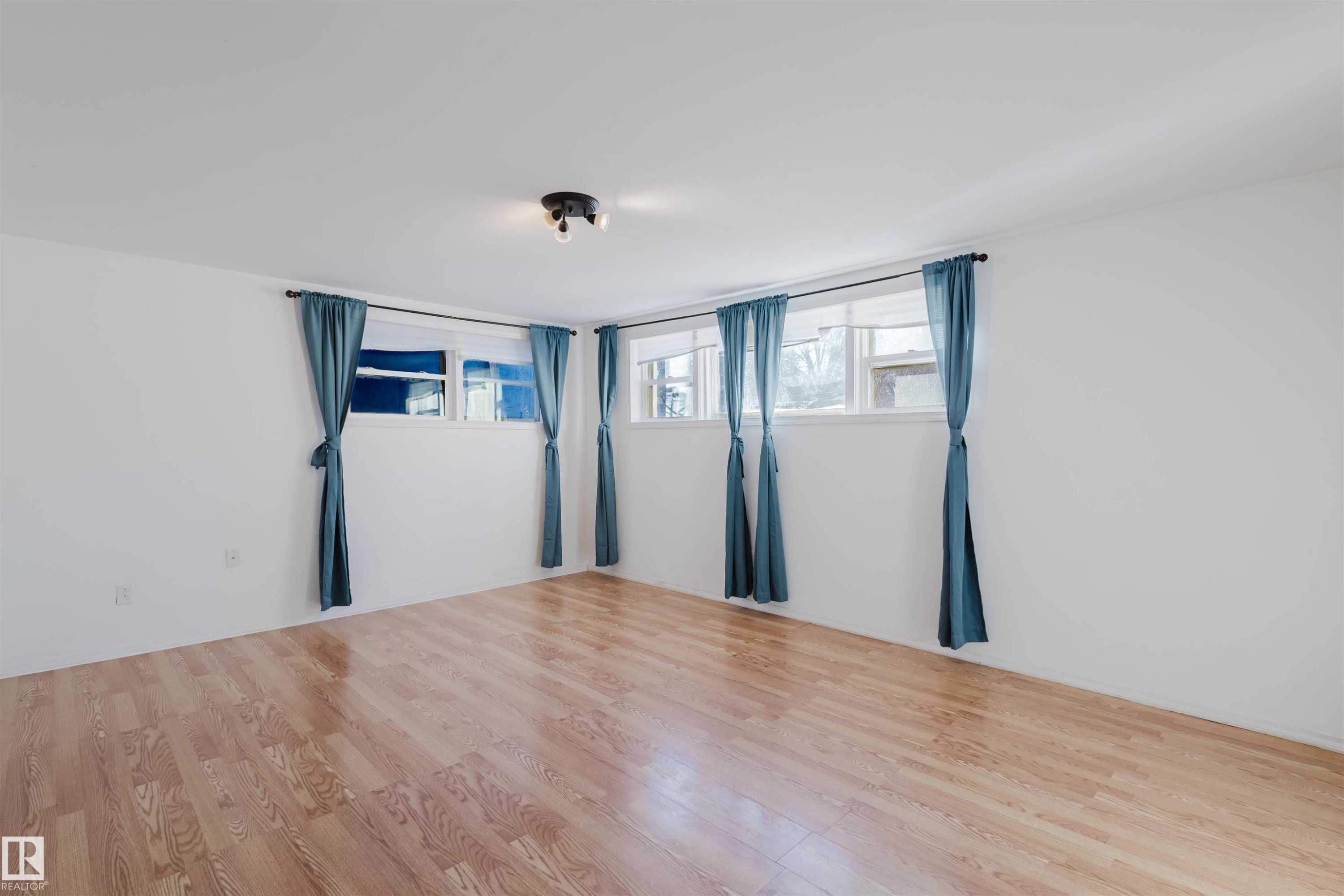 Hardwood-style flooring throughout a room with white walls and multiple windows - 10511 80 Street, Edmonton, AB - Indoor Photo Showing Other Room