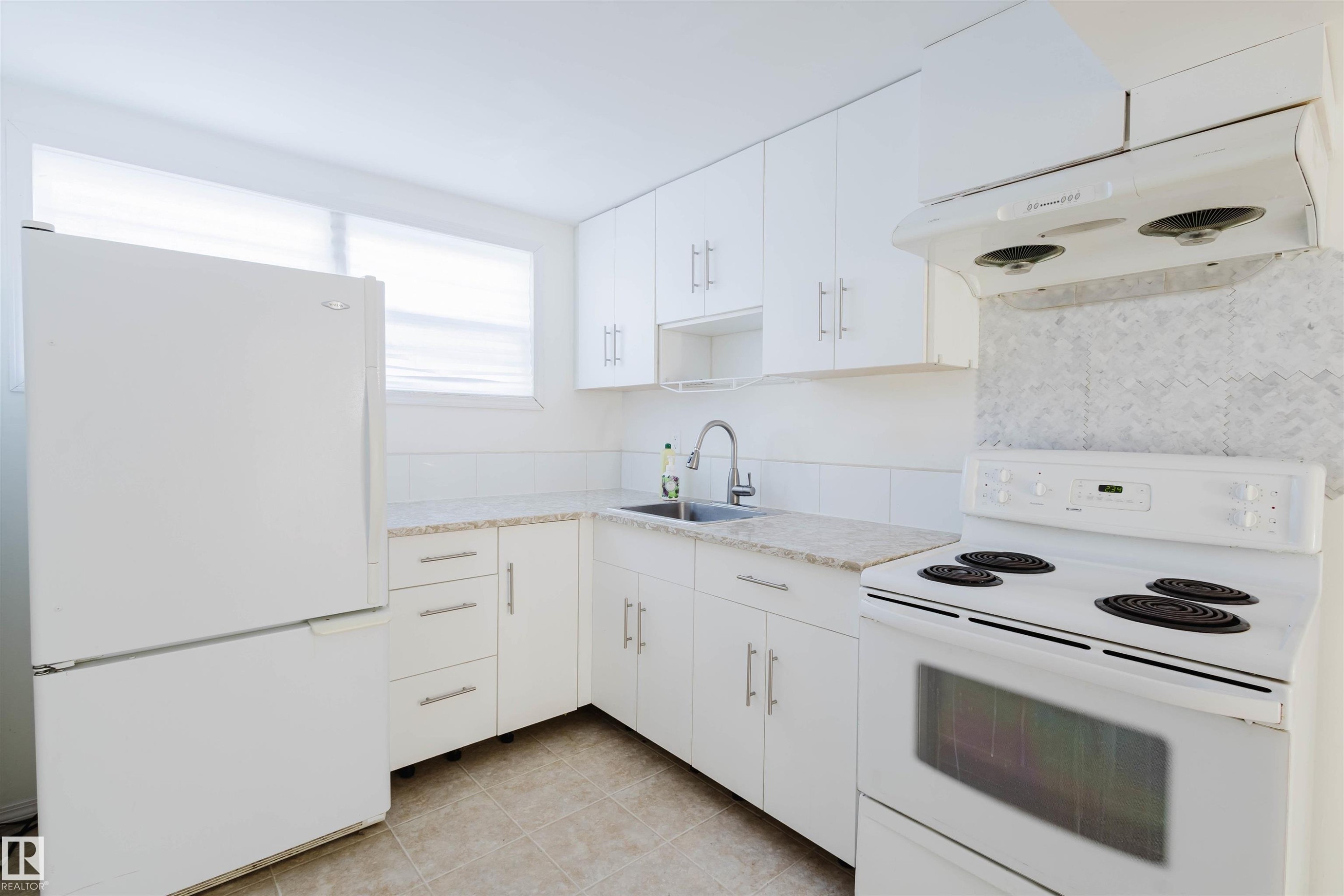 Bright kitchen featuring white cabinetry, light-toned countertops, a white range, and a white refrigerator - 10511 80 Street, Edmonton, AB - Indoor Photo Showing Kitchen