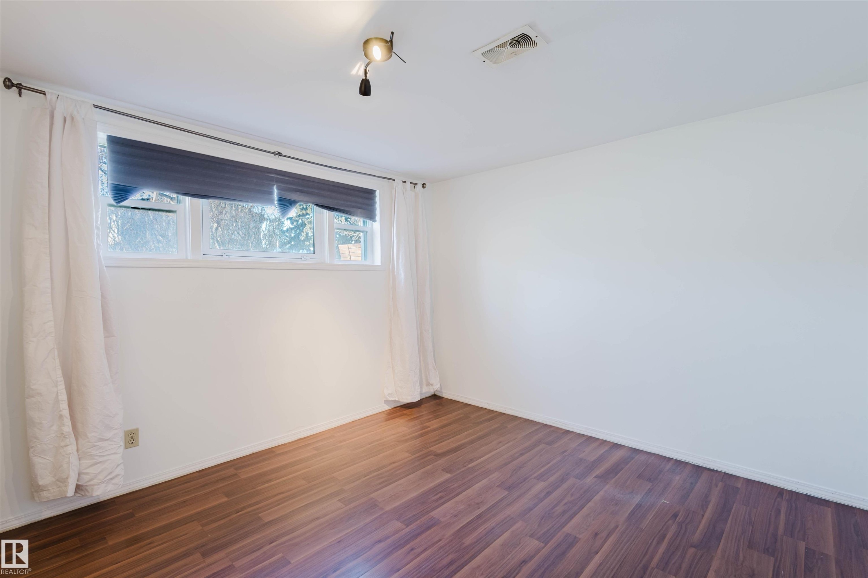 Interior room featuring wood-finish flooring, white walls, and a multi-pane window - 10511 80 Street, Edmonton, AB - Indoor Photo Showing Other Room