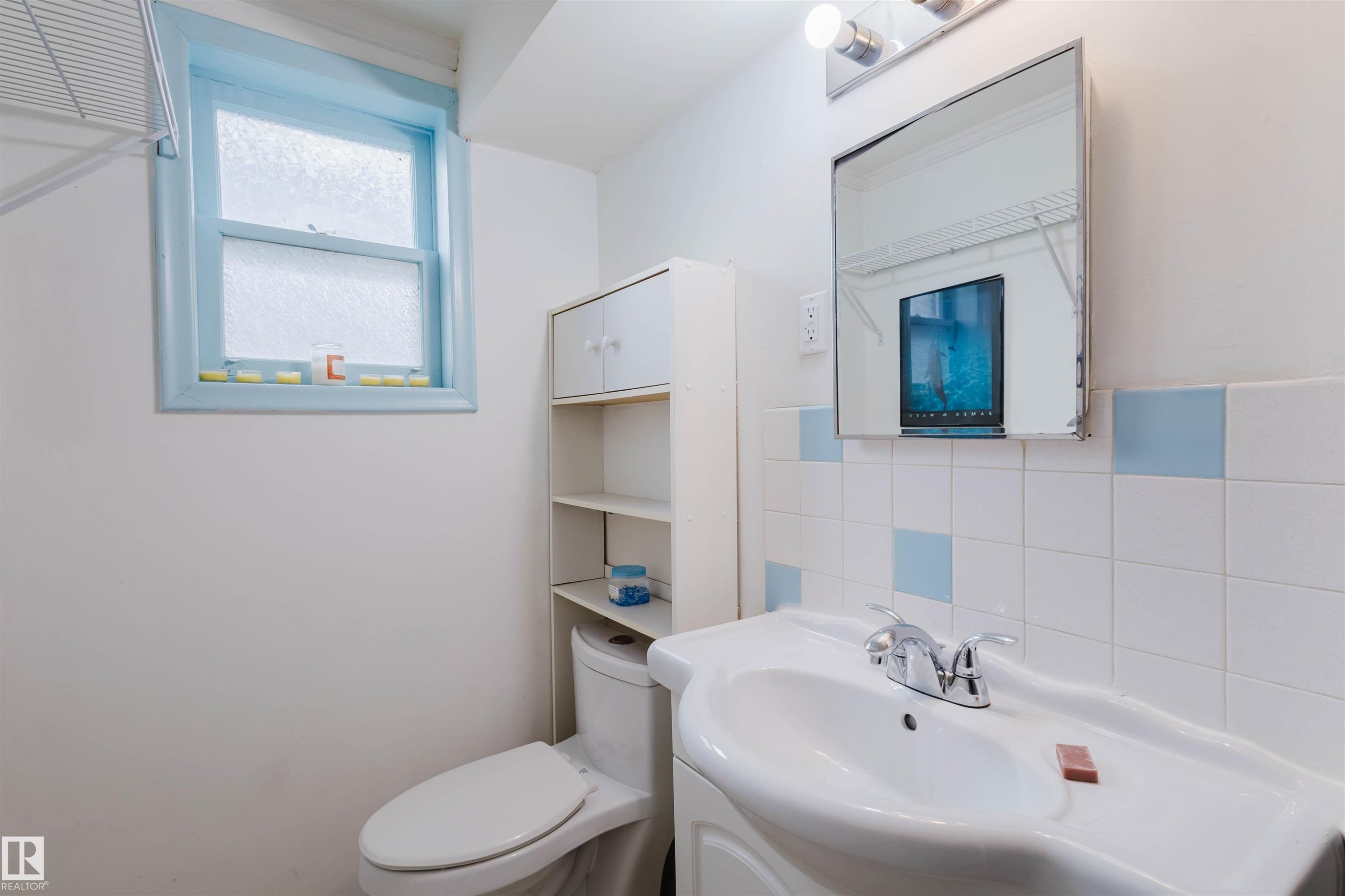 Bathroom featuring a wall-mounted sink, ceramic tile backsplash with accent squares, and a medicine cabinet with integrated lighting - 10511 80 Street, Edmonton, AB - Indoor Photo Showing Bathroom