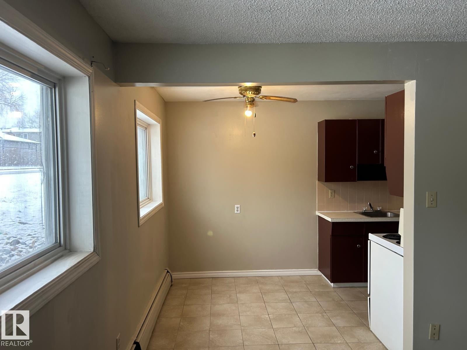 Kitchen and dining area featuring tiled flooring, a ceiling fan, and two windows providing natural light - #4 10164 150 St Nw, Edmonton, AB - Indoor