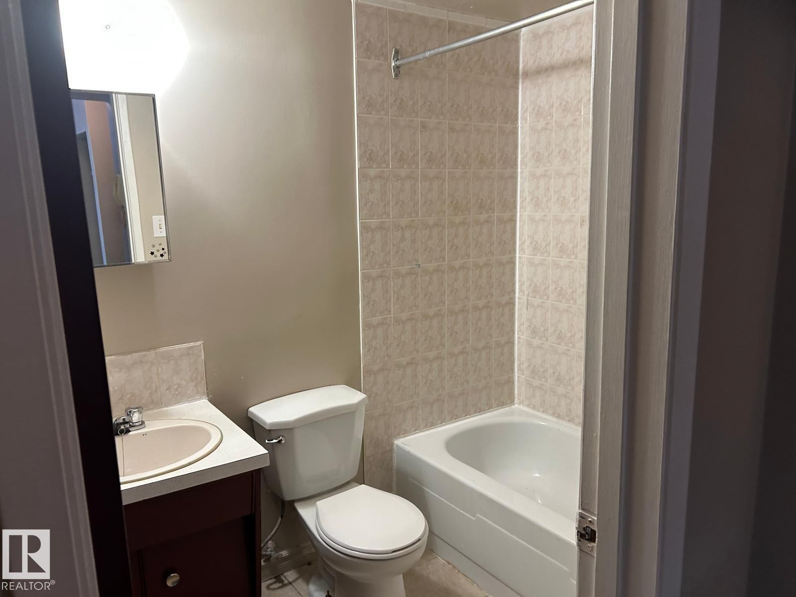Bathroom featuring a tiled shower and bathtub combination, a vanity with a sink, and a toilet - #4 10164 150 St Nw, Edmonton, AB - Indoor Photo Showing Bathroom