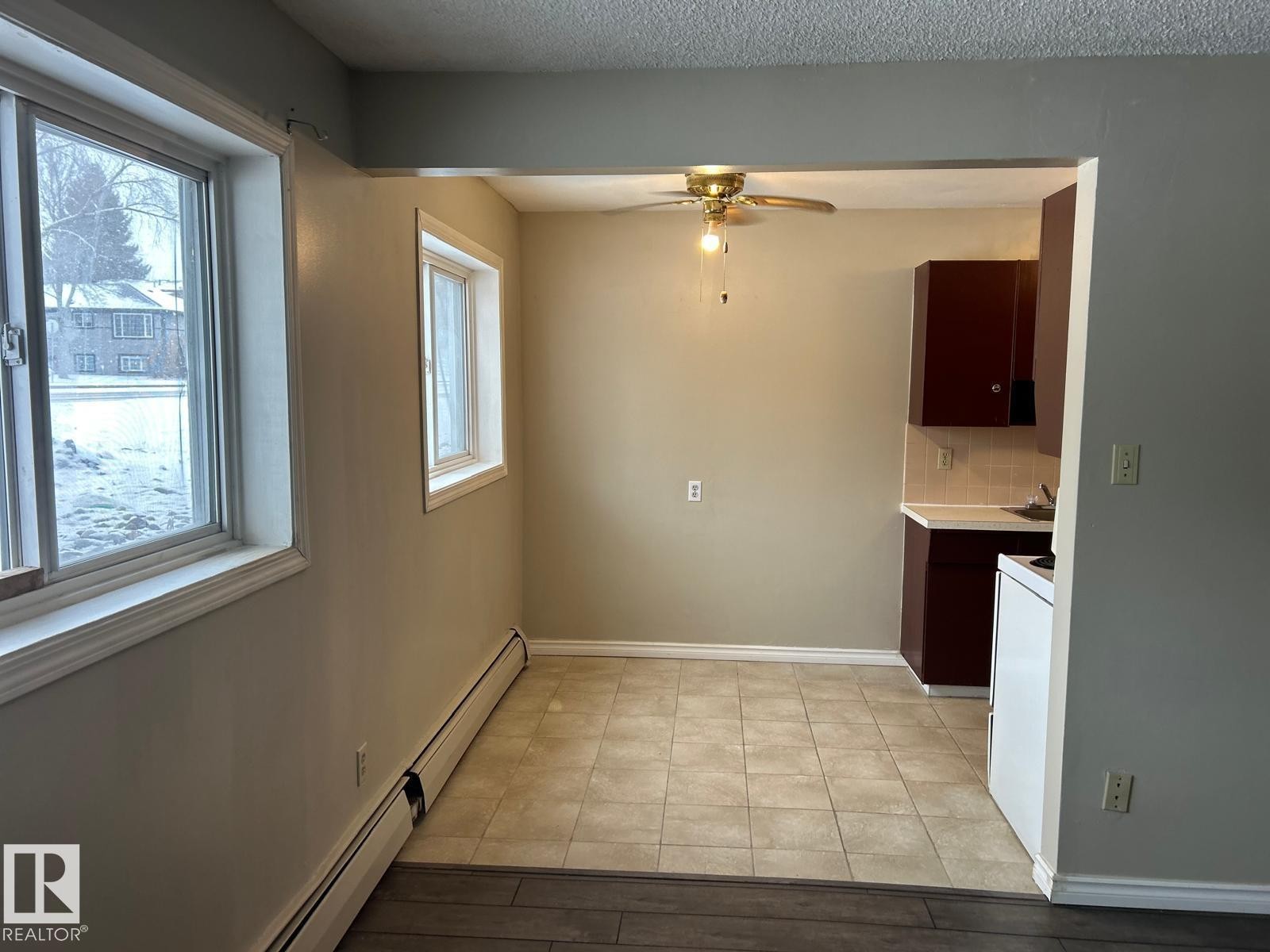 This property features a dining area with tiled flooring, a ceiling fan, and two windows providing natural light - #4 10164 150 St Nw, Edmonton, AB - Indoor