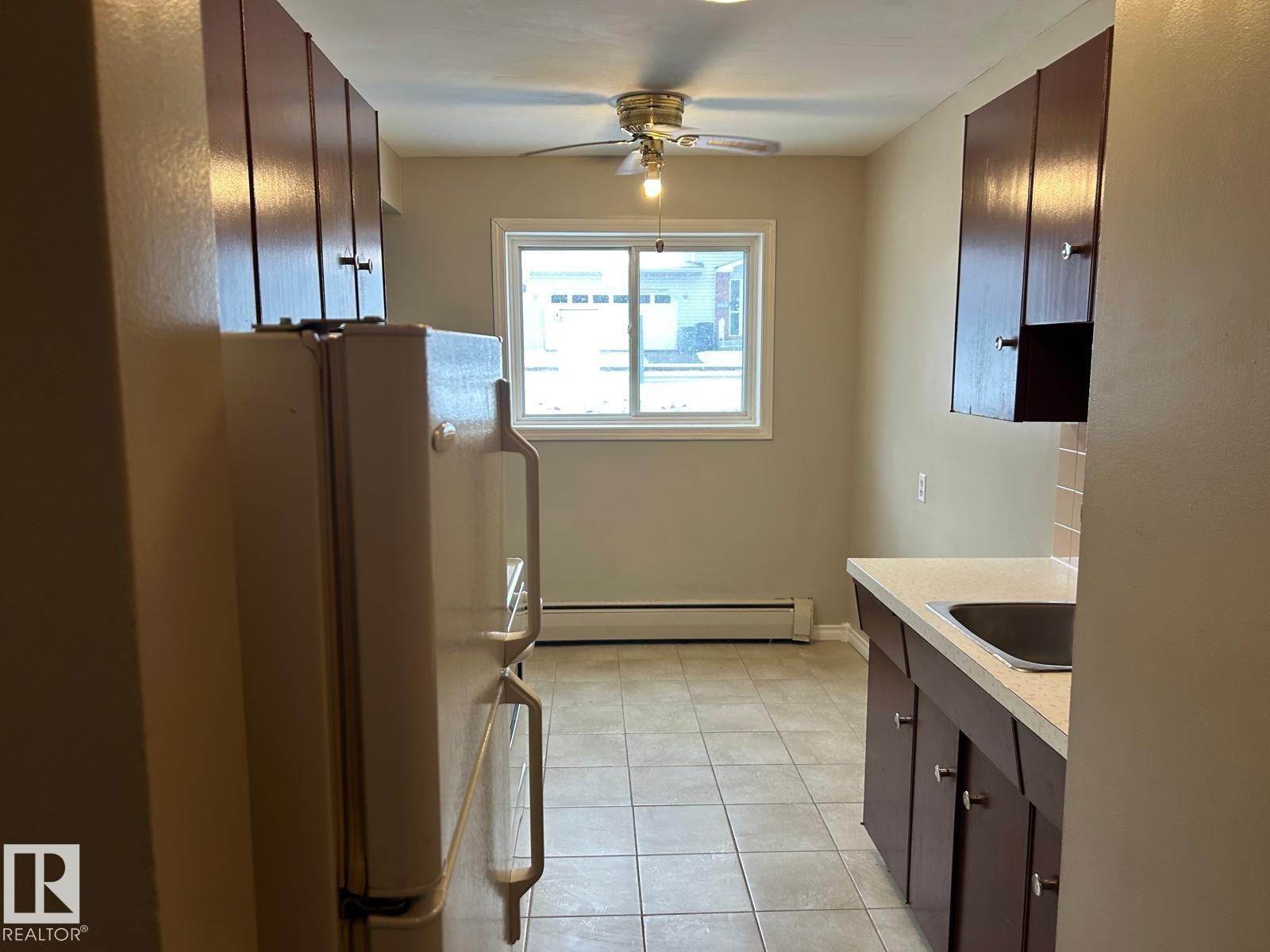 The kitchen features a window, a ceiling fan, and tiled flooring - #4 10164 150 St Nw, Edmonton, AB - Indoor Photo Showing Kitchen