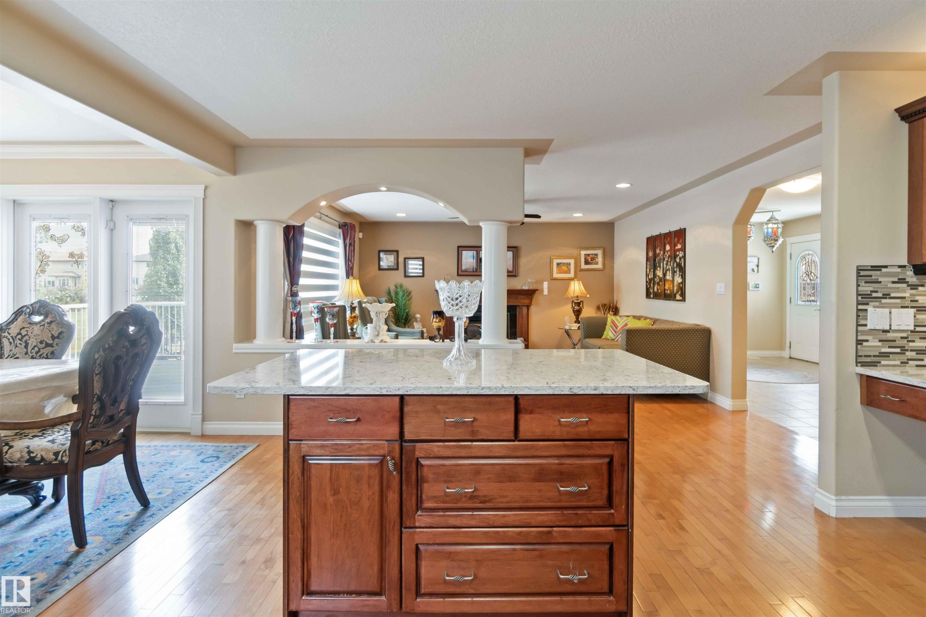 Kitchen island featuring a light-colored countertop and wood-finish cabinetry, set on wood-finish flooring - 6116 53 Avenue, Beaumont, AB - Indoor
