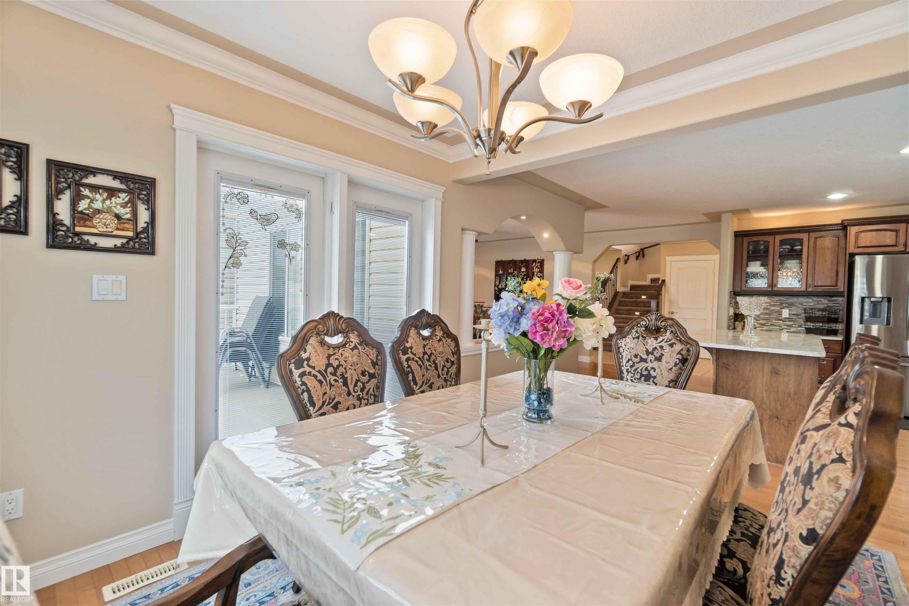 Dining area featuring wood-finish flooring, crown molding, and a five-light chandelier - 6116 53 Avenue, Beaumont, AB - Indoor Photo Showing Dining Room