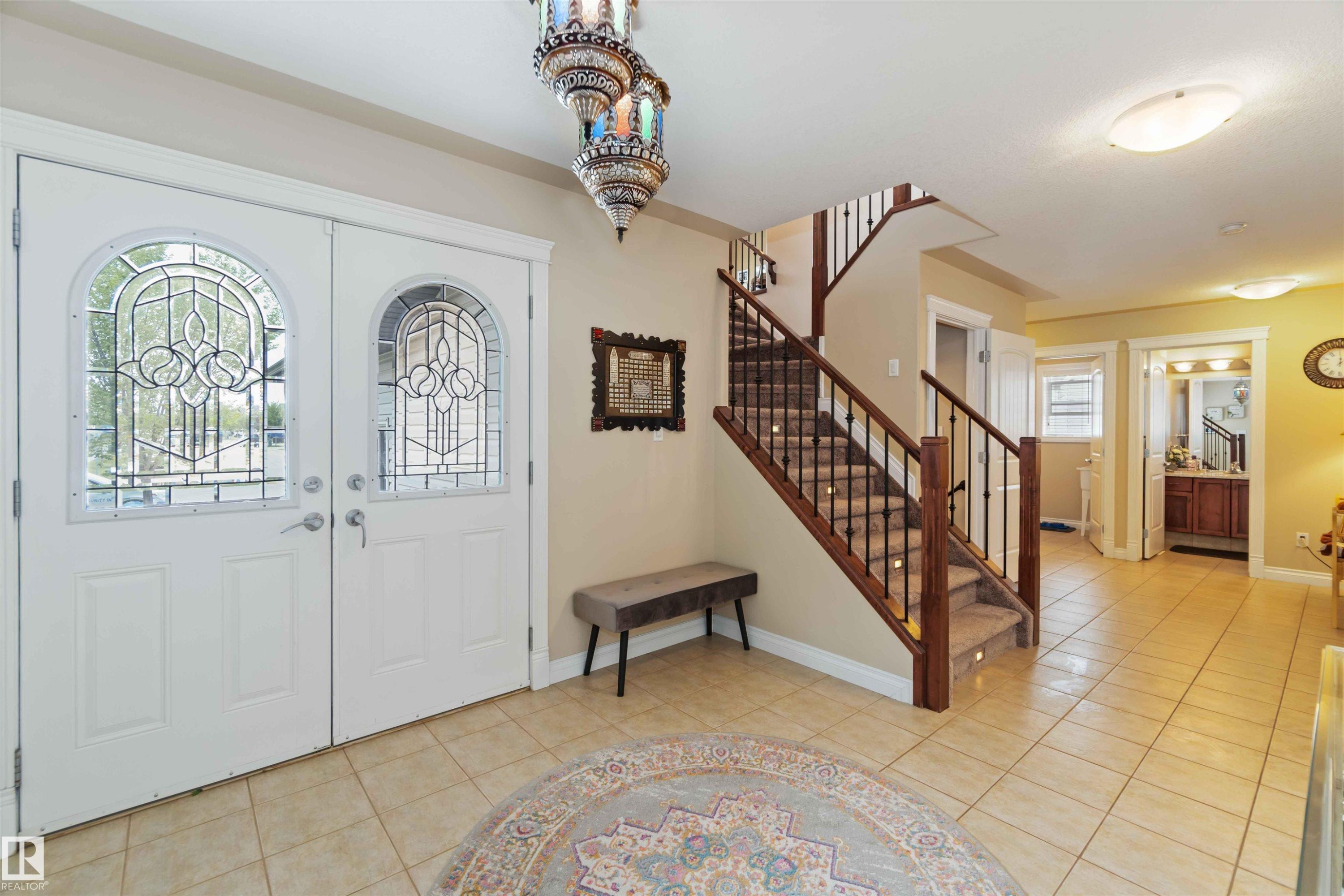 Entryway featuring double doors with decorative glass panels, a tiled floor, and a staircase with wood newel posts and metal balusters - 6116 53 Avenue, Beaumont, AB - Indoor Photo Showing Other Room