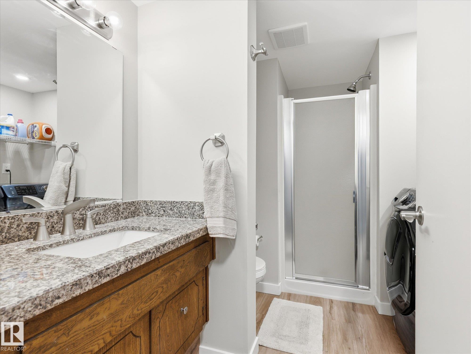 Bathroom vanity featuring a granite countertop with an undermount sink and a wood-finish cabinet - 18627 62A Avenue, Edmonton, AB - Indoor Photo Showing Bathroom