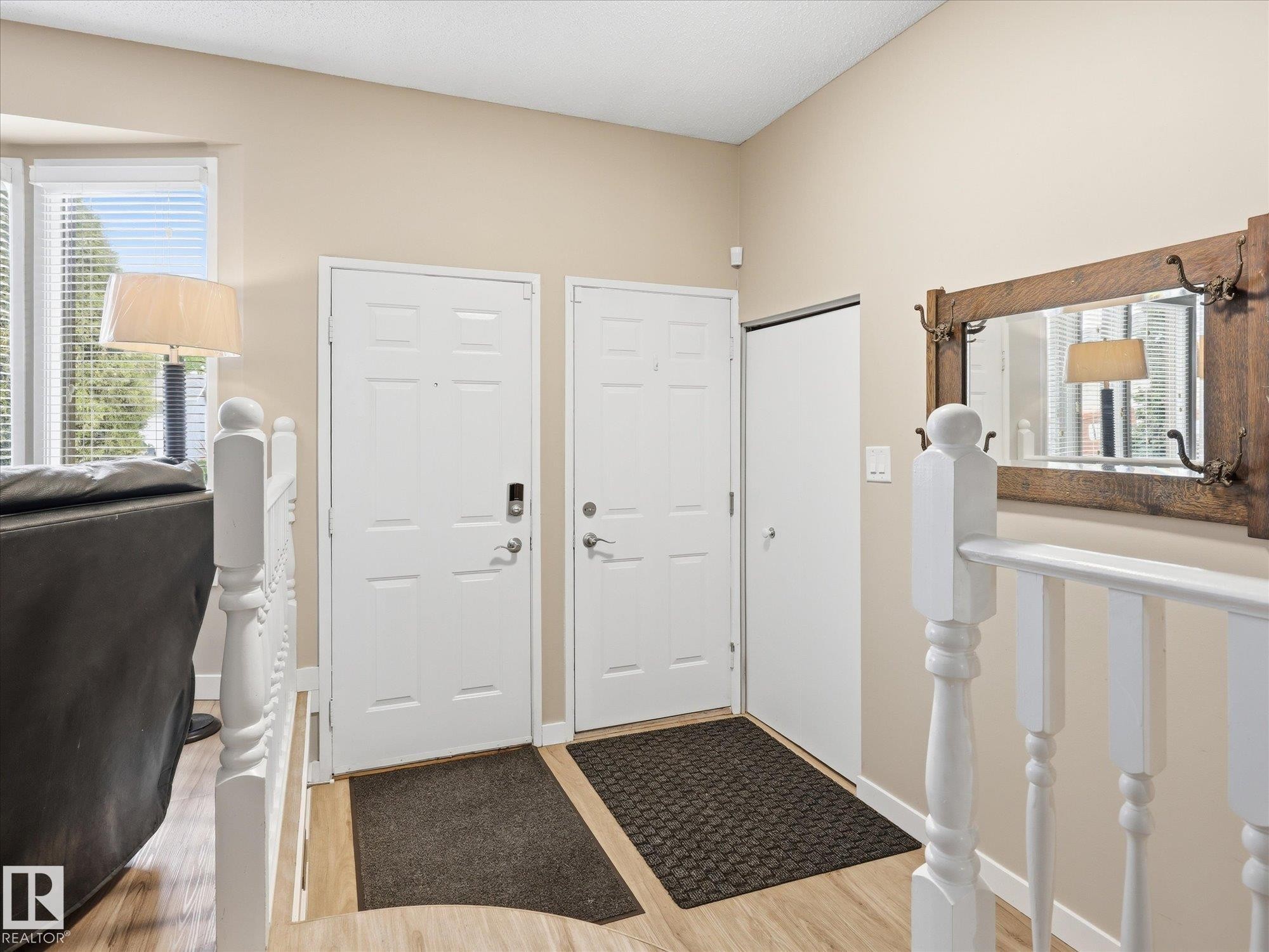 Entryway featuring wood-finish flooring, white paneled doors, and a staircase with white balusters - 18627 62A Avenue, Edmonton, AB - Indoor Photo Showing Other Room