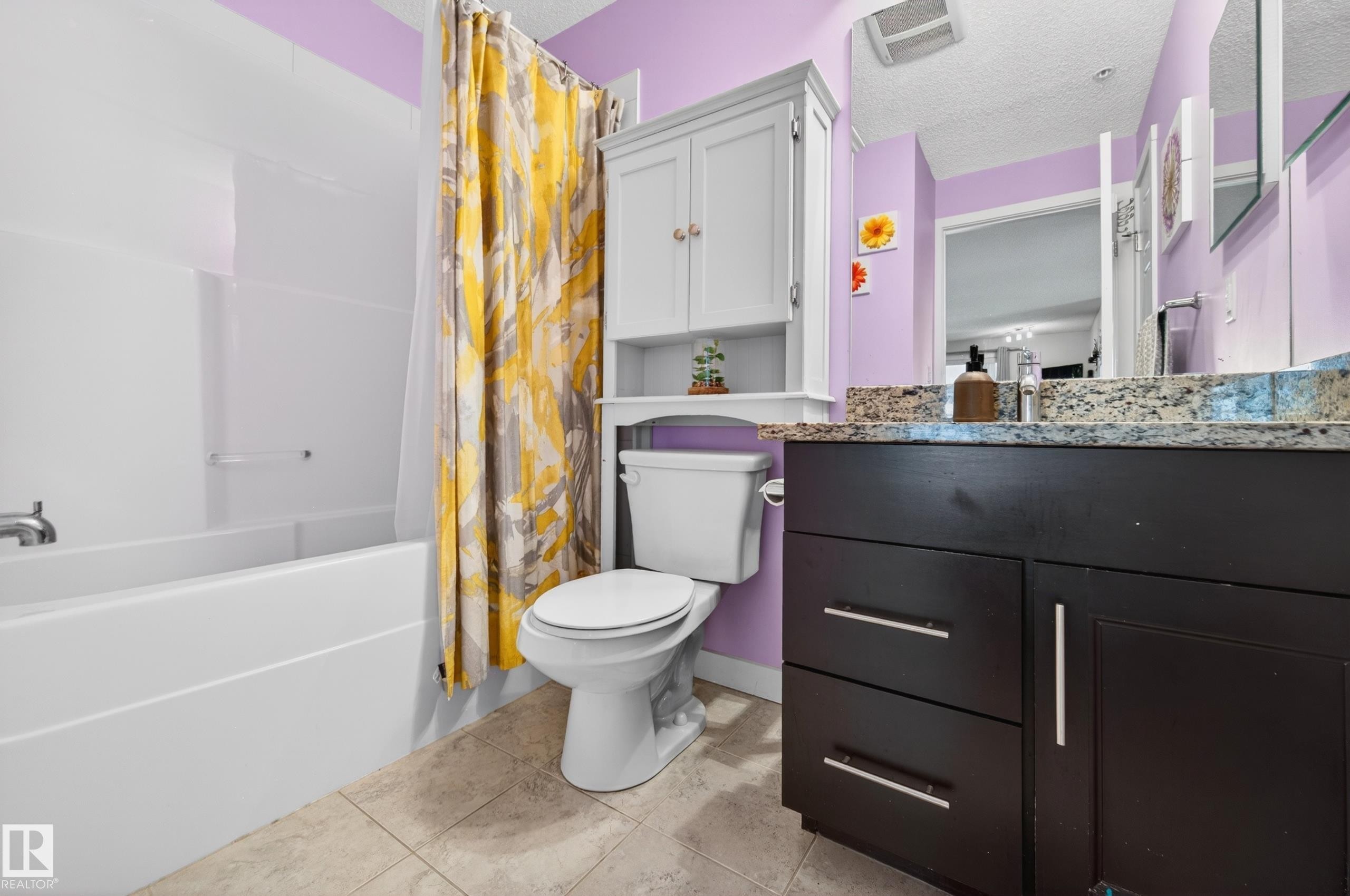 Bathroom featuring a white tub and shower combination, dark wood-finish vanity with a light-colored countertop, and a built-in wall cabinet above the toilet - 340 6076 Schonsee Way, Edmonton, AB - Indoor Photo Showing Bathroom