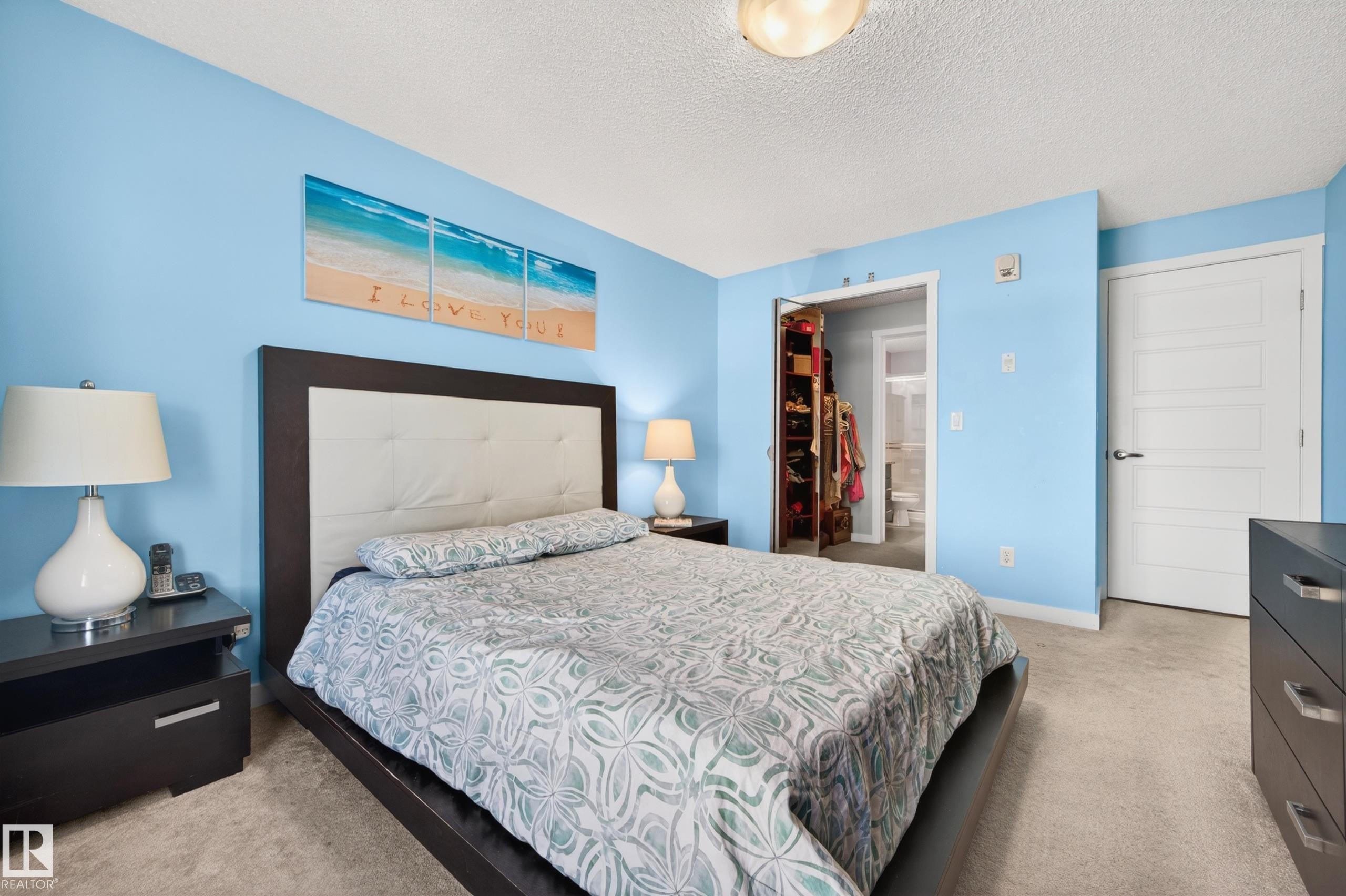 Carpeted bedroom featuring light blue walls, a white paneled door, and a built-in closet with sliding doors - 340 6076 Schonsee Way, Edmonton, AB - Indoor Photo Showing Bedroom