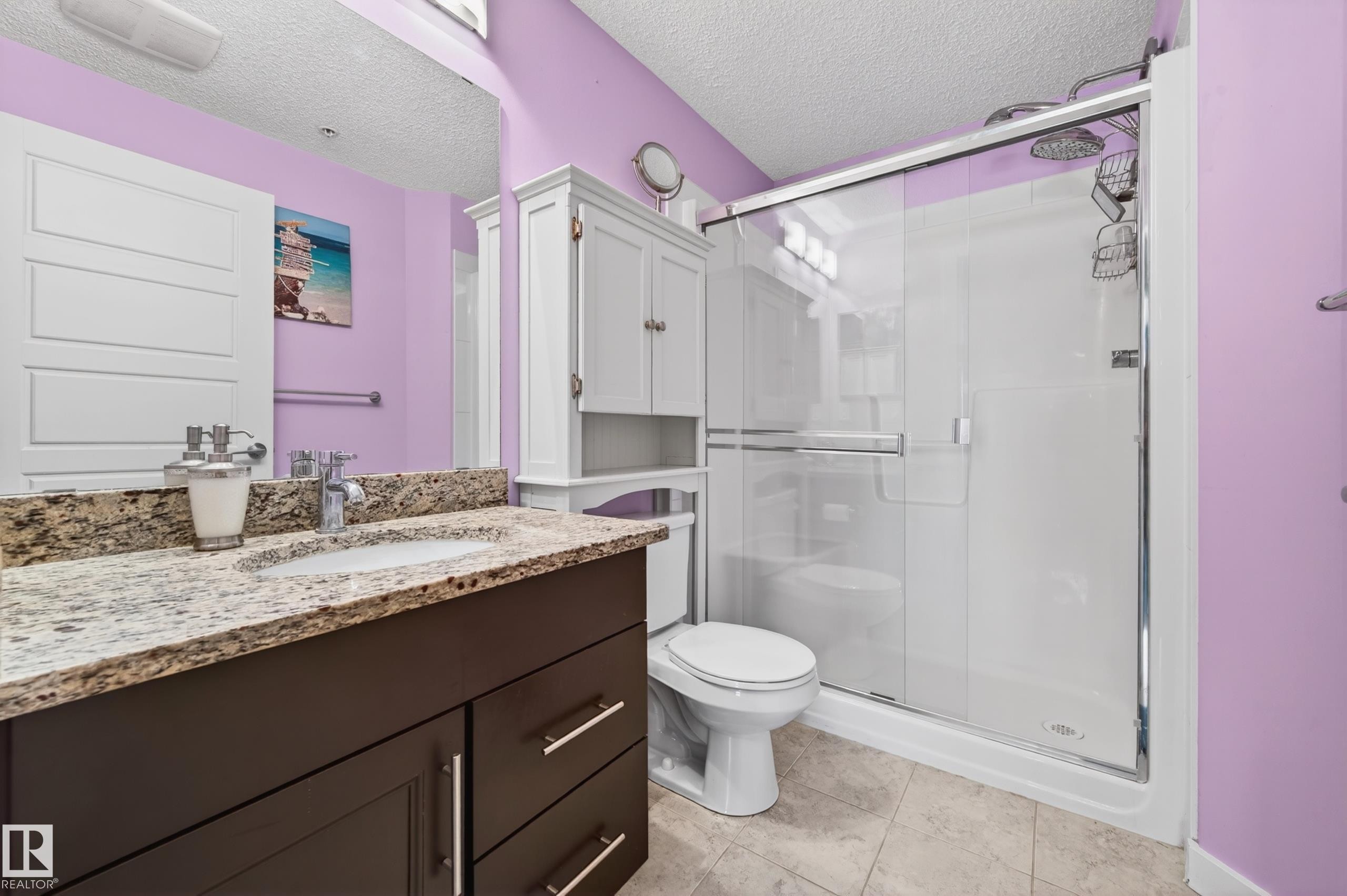 Spacious bathroom featuring a dark wood-finish vanity with a granite-style countertop and integrated sink - 340 6076 Schonsee Way, Edmonton, AB - Indoor Photo Showing Bathroom