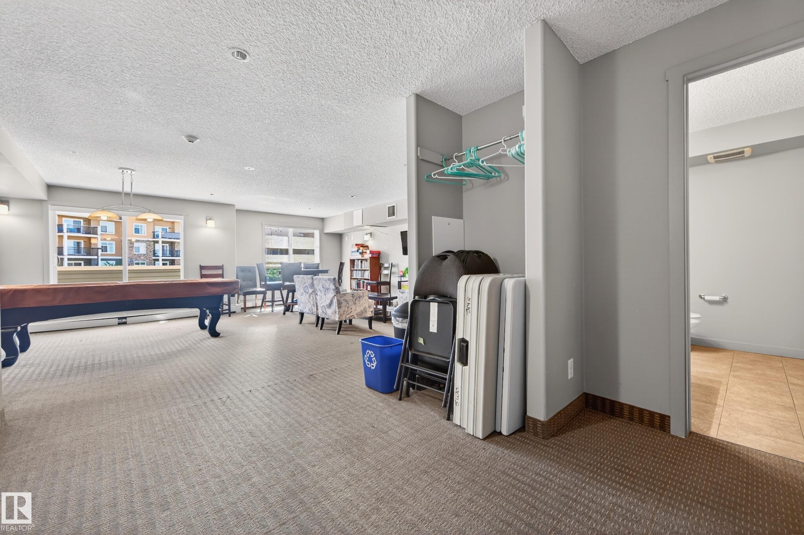 Spacious communal area featuring patterned carpet flooring and a built-in storage alcove - 340 6076 Schonsee Way, Edmonton, AB - Indoor