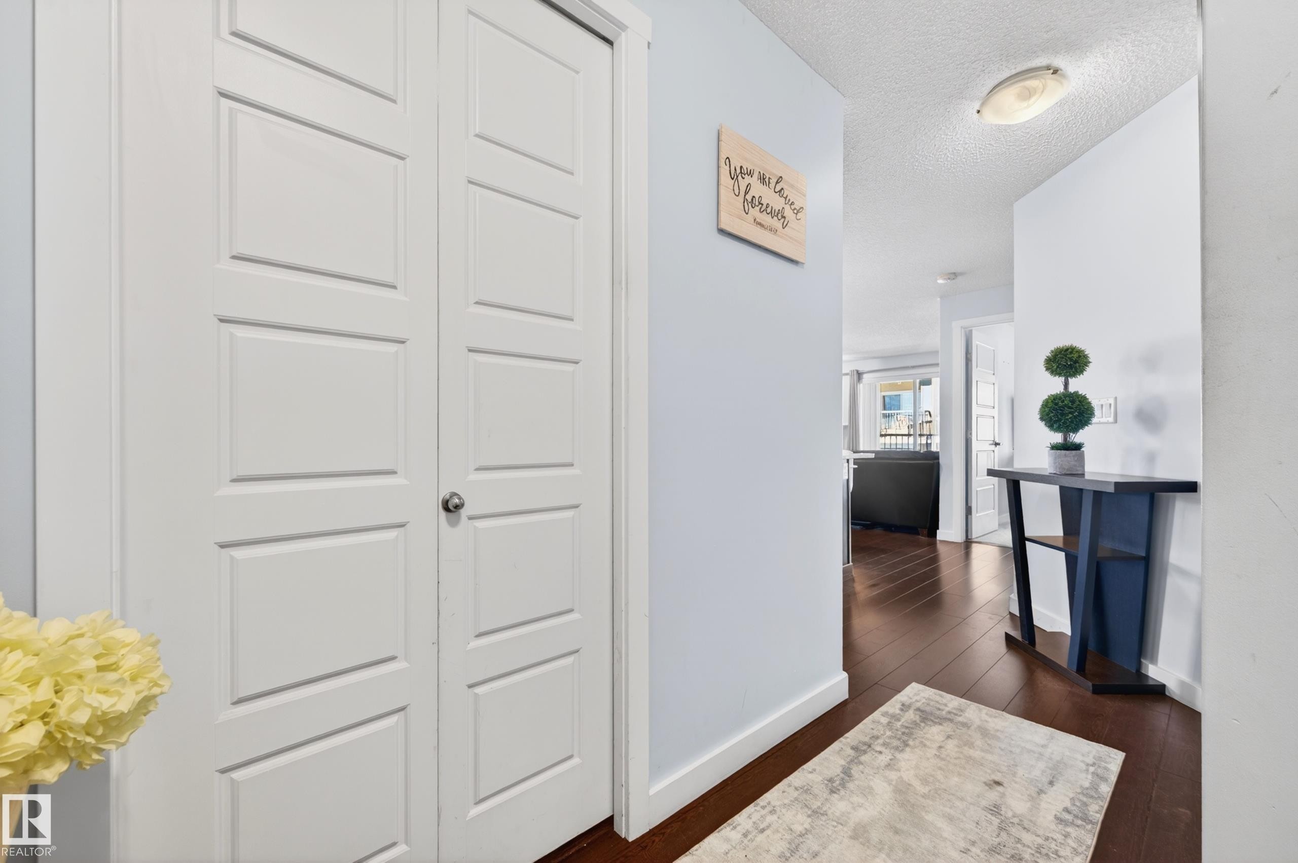 White paneled bifold closet doors, wood-finish flooring, and light blue wall tones - 340 6076 Schonsee Way, Edmonton, AB - Indoor Photo Showing Other Room