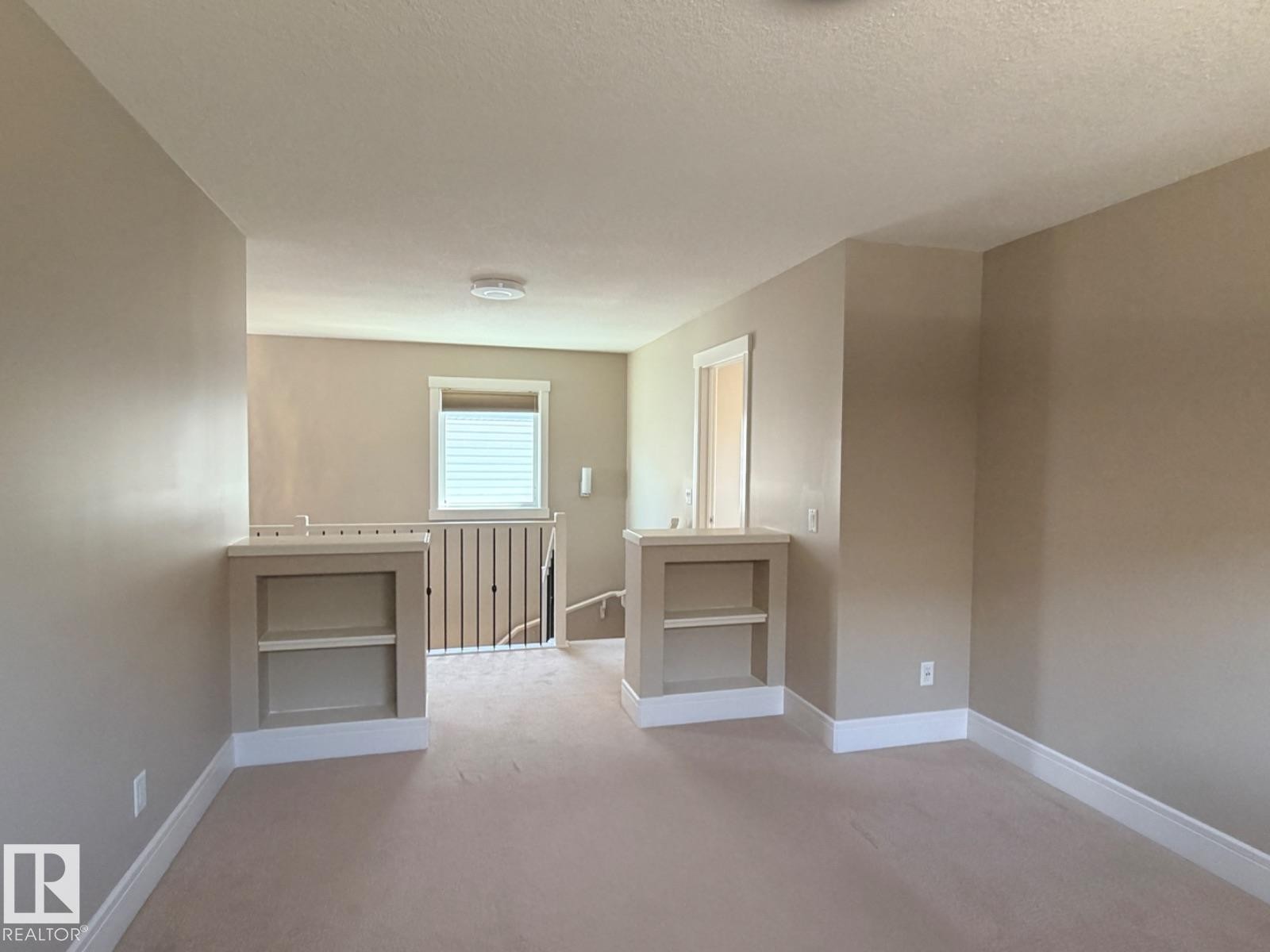 Carpeted loft area featuring built-in shelving, neutral wall tones, white trim, and a window with blinds - 648 178 Street, Edmonton, AB