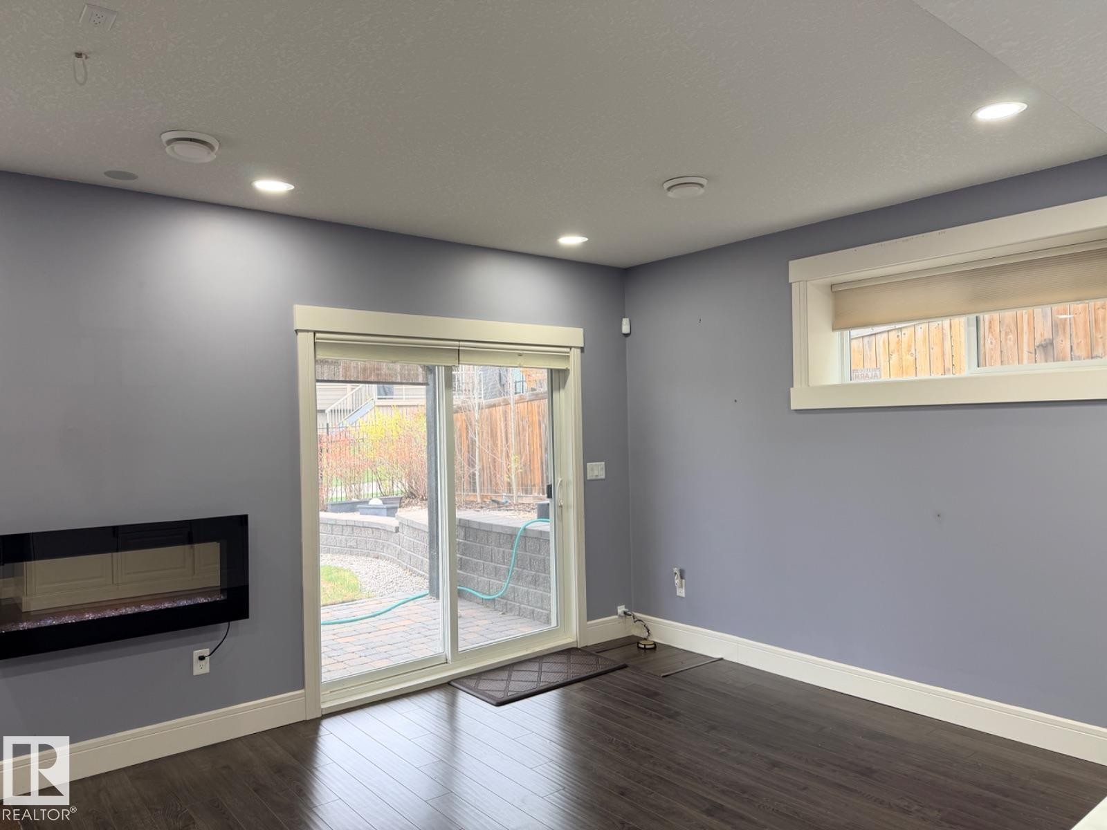 Interior space featuring wood-finish flooring, recessed ceiling lighting, and a wall-mounted linear fireplace - 648 178 Street, Edmonton, AB