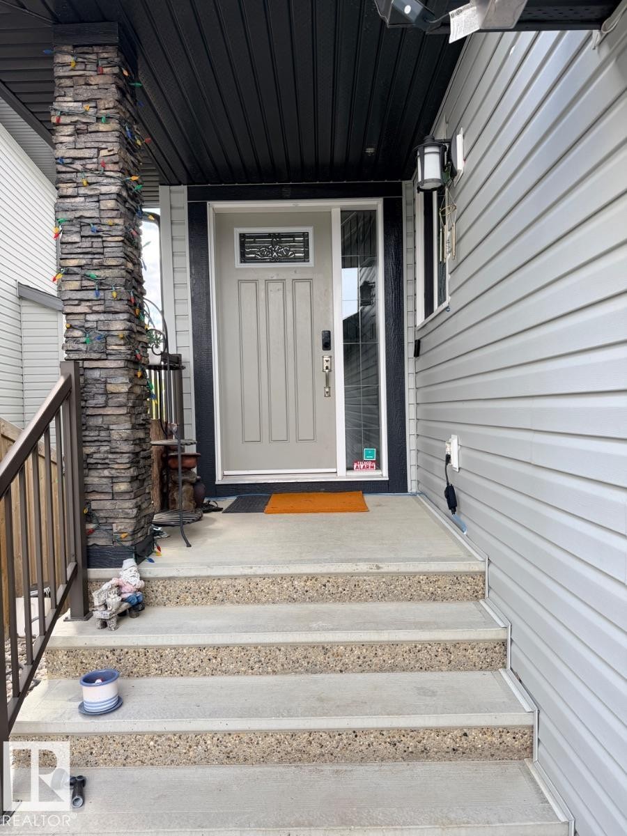 Front entry featuring a light-colored main door with decorative glass inlay and a sidelight - 648 178 Street, Edmonton, AB