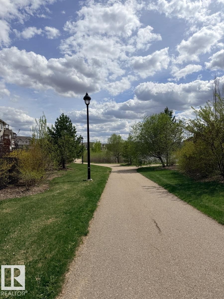 Paved pedestrian pathway bordered by manicured grass and mature trees - 648 178 Street, Edmonton, AB