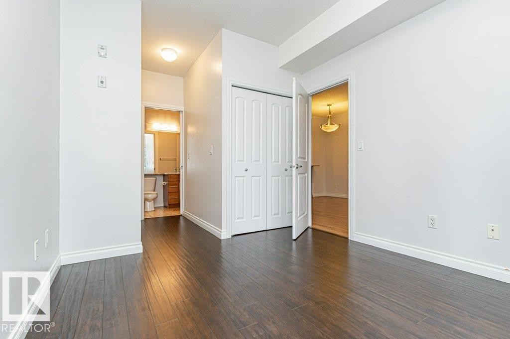 Room featuring dark wood-finish flooring, white walls, and white baseboards - #145 10121 80 Av Nw, Edmonton, AB - Indoor Photo Showing Other Room