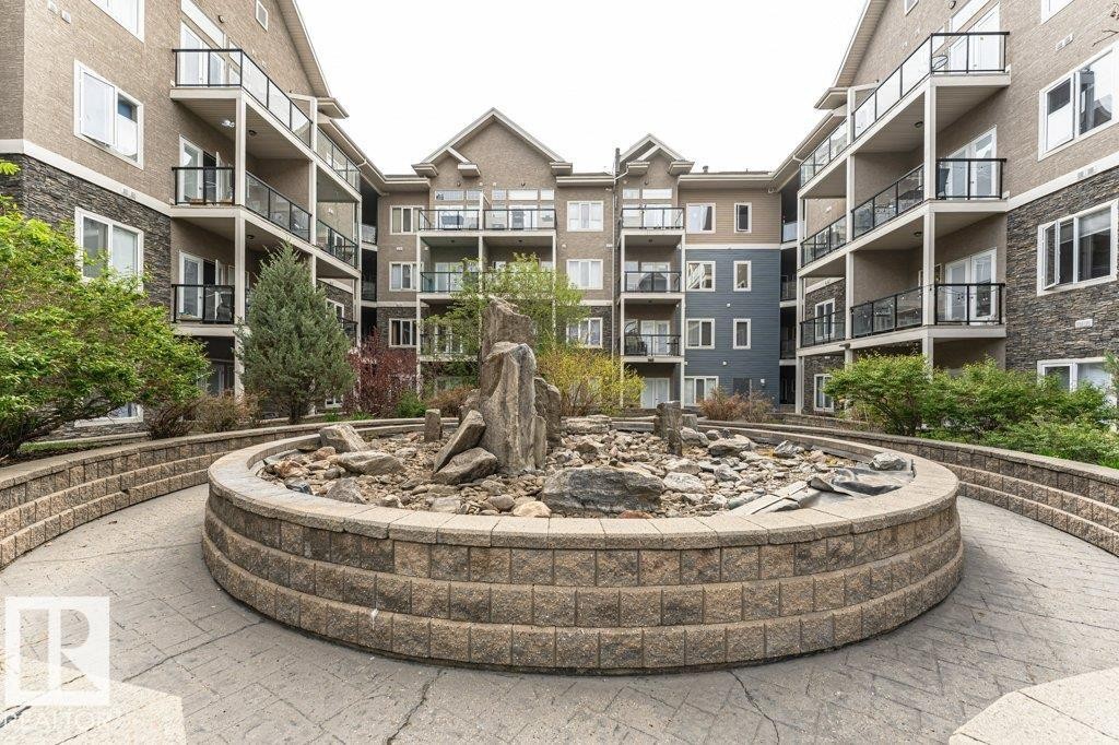 Central courtyard featuring a decorative rock garden and mature landscaping - #145 10121 80 Av Nw, Edmonton, AB - Outdoor With Facade