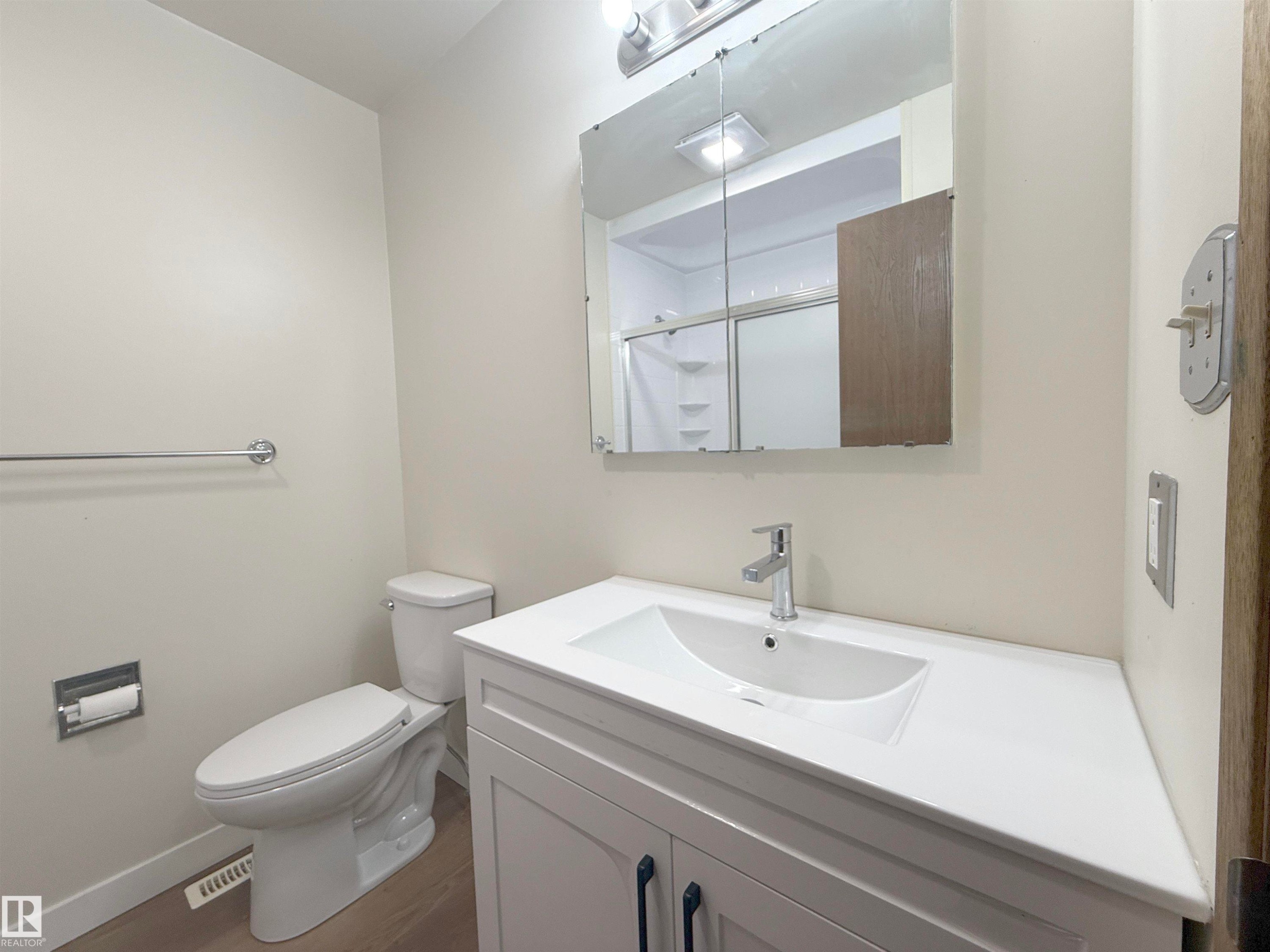 Modern bathroom featuring a single vanity with a white countertop and integrated sink, chrome faucet, and storage cabinetry with dark hardware - 1731 51 Street, Edmonton, AB - Indoor Photo Showing Bathroom