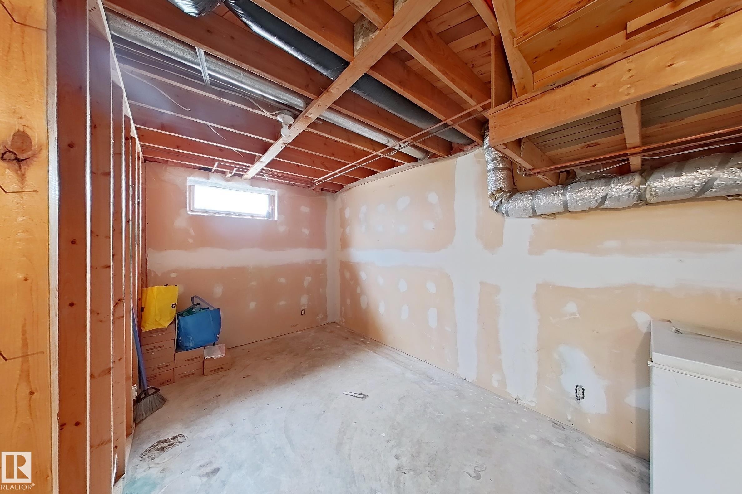 Framed unfinished basement space with exposed ceiling joists, concrete flooring, and a single window providing natural light - 1731 51 Street, Edmonton, AB - Indoor Photo Showing Basement