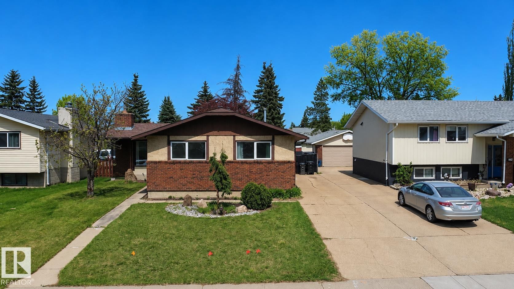 Bungalow-style residence featuring a brick and stucco facade with white-framed windows, a brown roof, and a concrete driveway - 1731 51 Street, Edmonton, AB - Outdoor