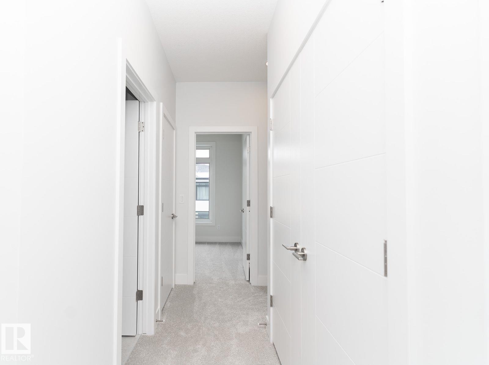 Hallway featuring light gray carpeting, white walls, and contemporary panel doors with brushed nickel hardware - 53 7121 May Crescent, Edmonton, AB - Indoor Photo Showing Other Room