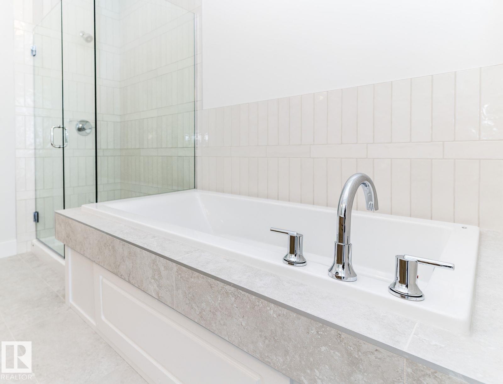 Built-in soaking tub with chrome fixtures, a stone-finish deck, and surrounding wainscoting - 53 7121 May Crescent, Edmonton, AB - Indoor Photo Showing Bathroom
