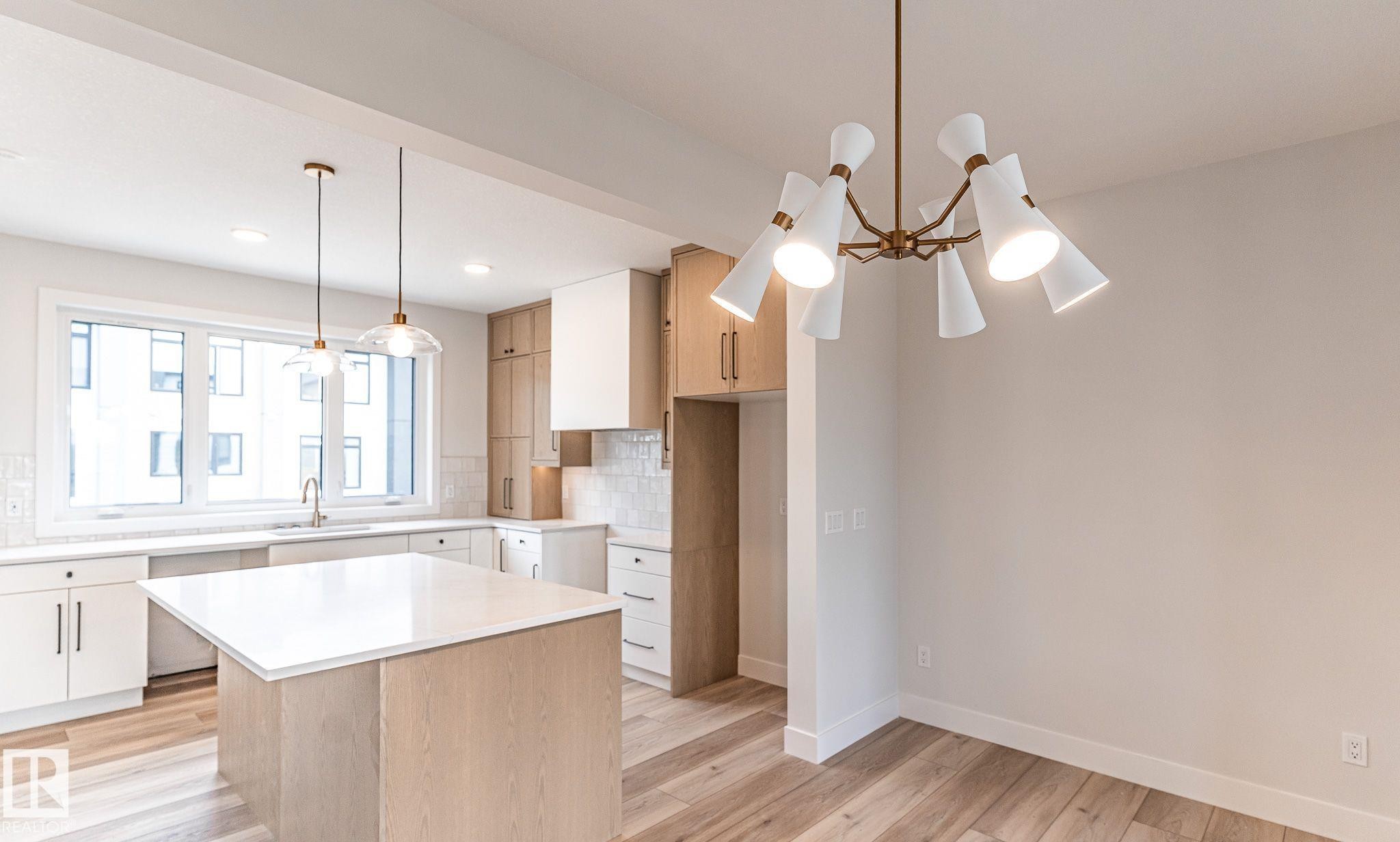 Open-concept living area with wood-finish flooring, a contemporary bronze chandelier, and recessed lighting - 53 7121 May Crescent, Edmonton, AB - Indoor Photo Showing Kitchen