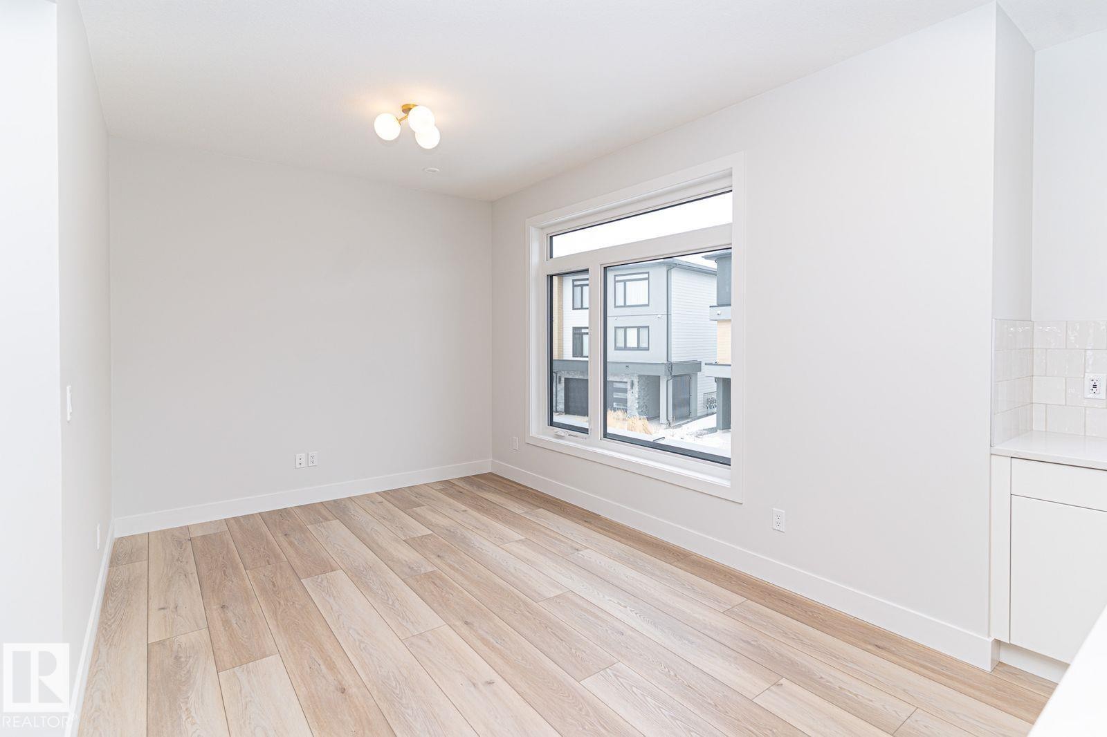 Bright room featuring light wood-finish flooring, white walls, and a large window - 53 7121 May Crescent, Edmonton, AB - Indoor Photo Showing Other Room