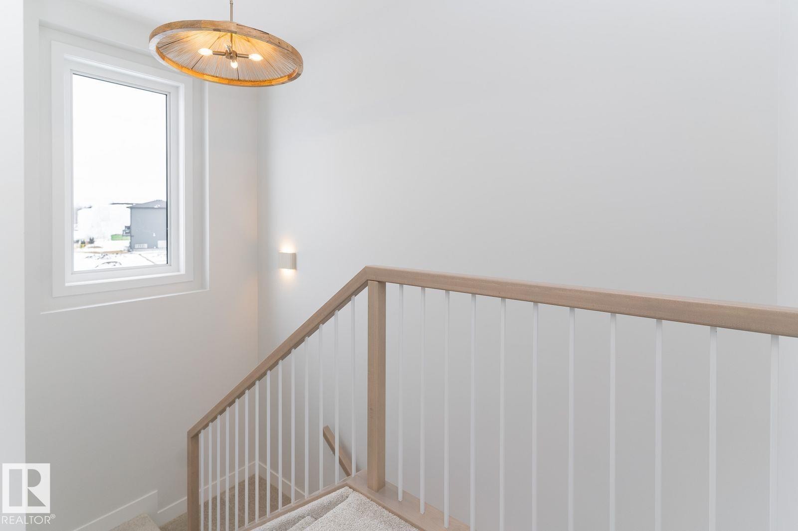 Staircase featuring a light wood-finish handrail, white balusters, and neutral-toned carpeted treads - 53 7121 May Crescent, Edmonton, AB - Indoor Photo Showing Other Room