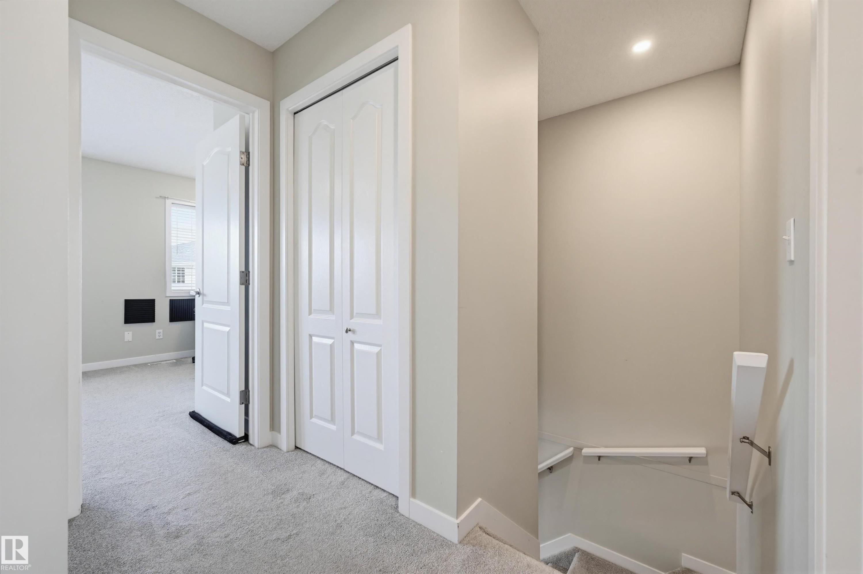 Carpeted hallway with a white bi-fold closet door and recessed lighting - 11 3380 28A Avenue Nw, Edmonton, AB - Indoor Photo Showing Other Room