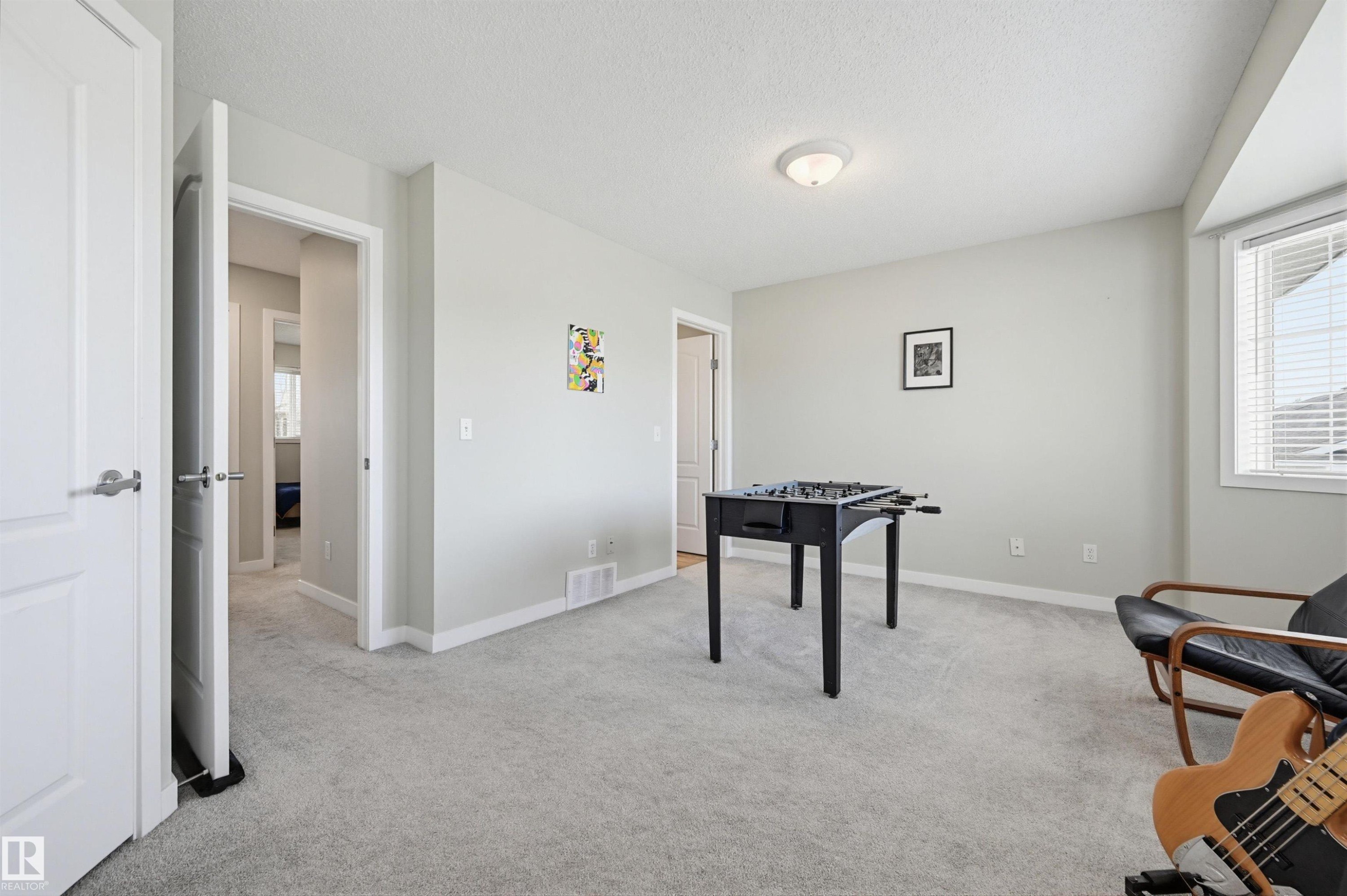Carpeted room featuring light gray wall paint, white baseboards, and a semi-flush mount ceiling light - 11 3380 28A Avenue Nw, Edmonton, AB - Indoor