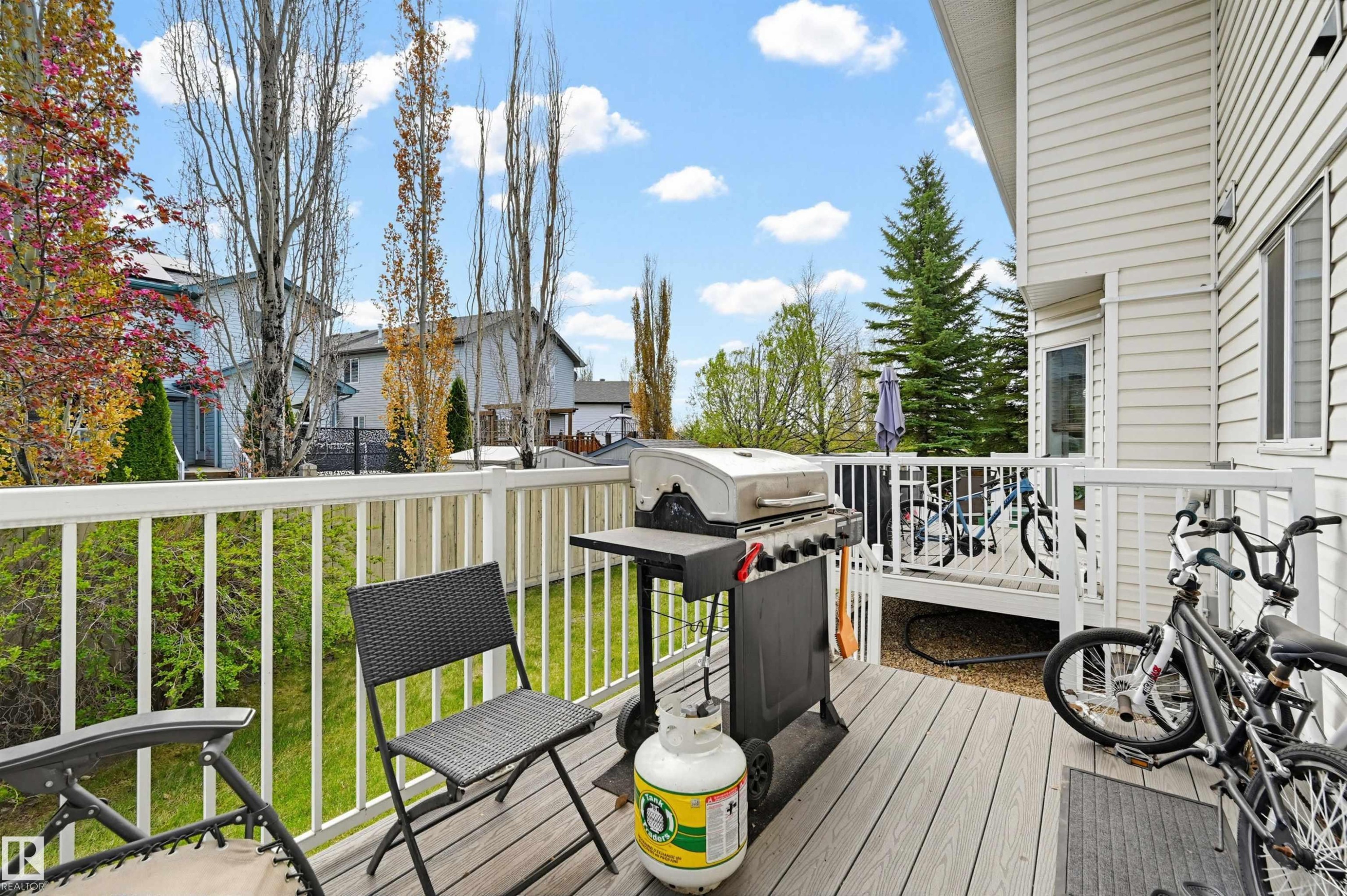 Composite wood deck with white railing, featuring siding exterior and visible landscaping - 11 3380 28A Avenue Nw, Edmonton, AB - Outdoor With View