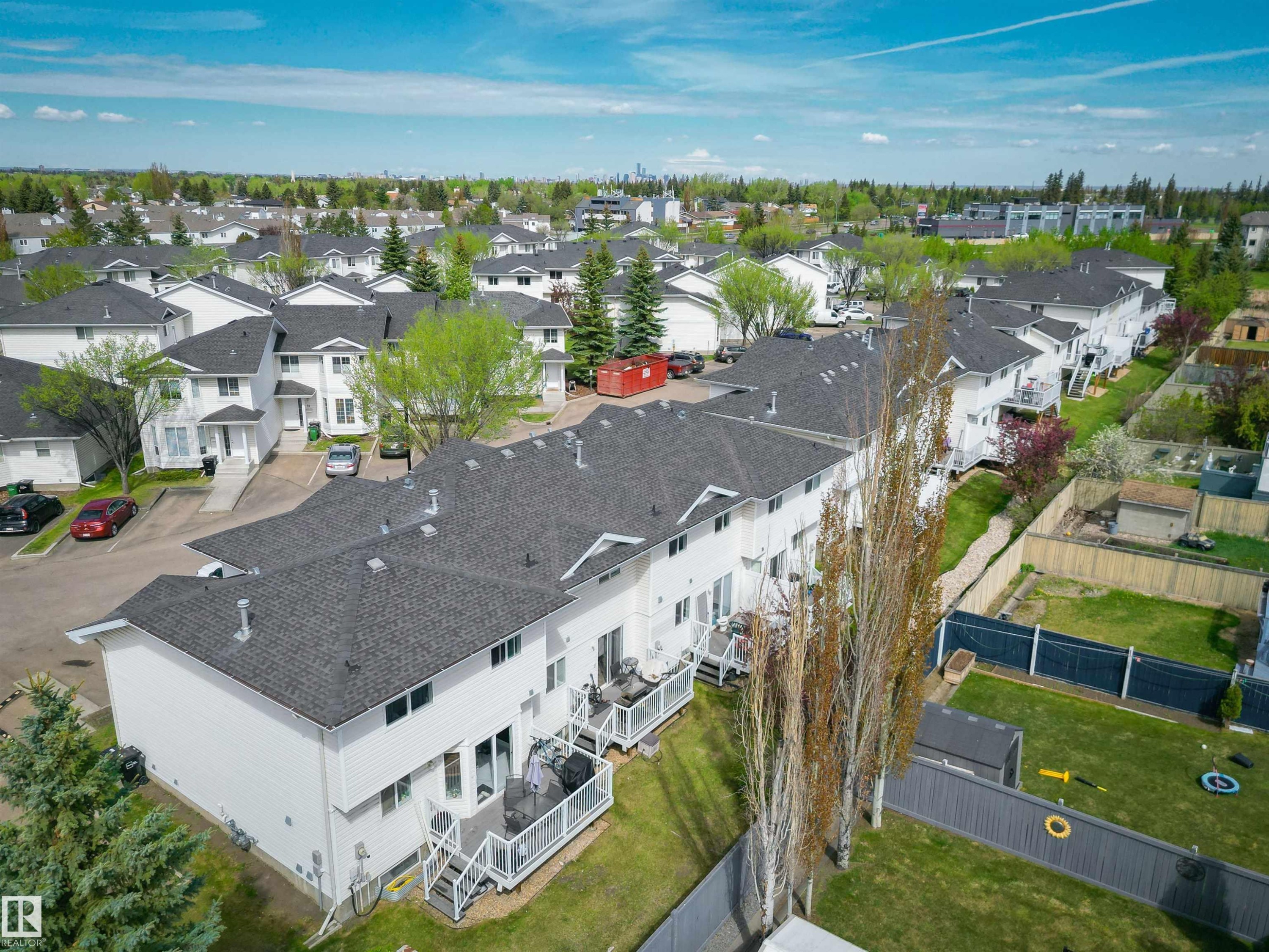 Residential complex featuring multiple white-sided townhomes with dark shingled roofs - 11 3380 28A Avenue Nw, Edmonton, AB - Outdoor With View