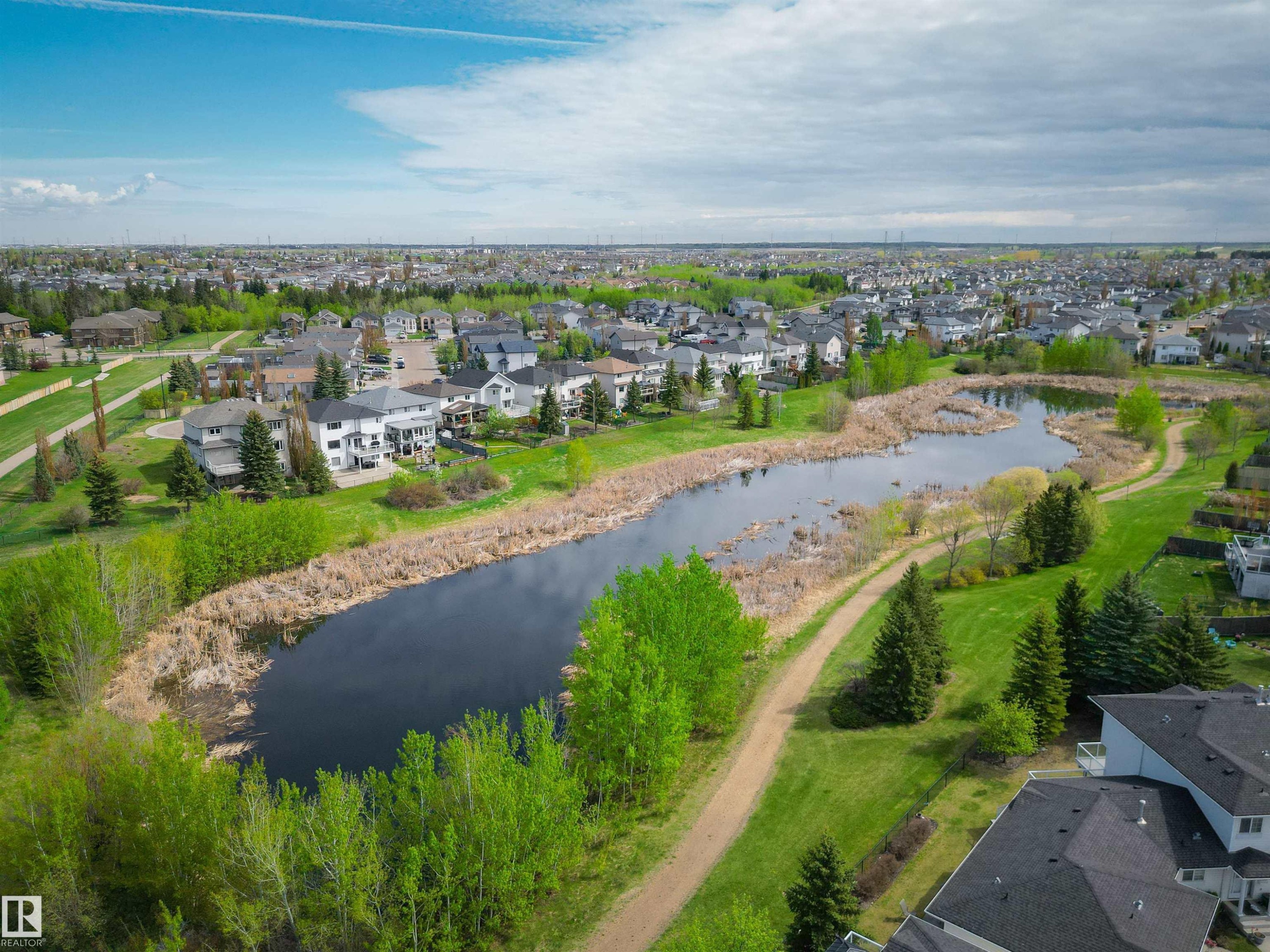 Expansive suburban landscape featuring a natural pond surrounded by green spaces and residential properties - 11 3380 28A Avenue Nw, Edmonton, AB - Outdoor With View