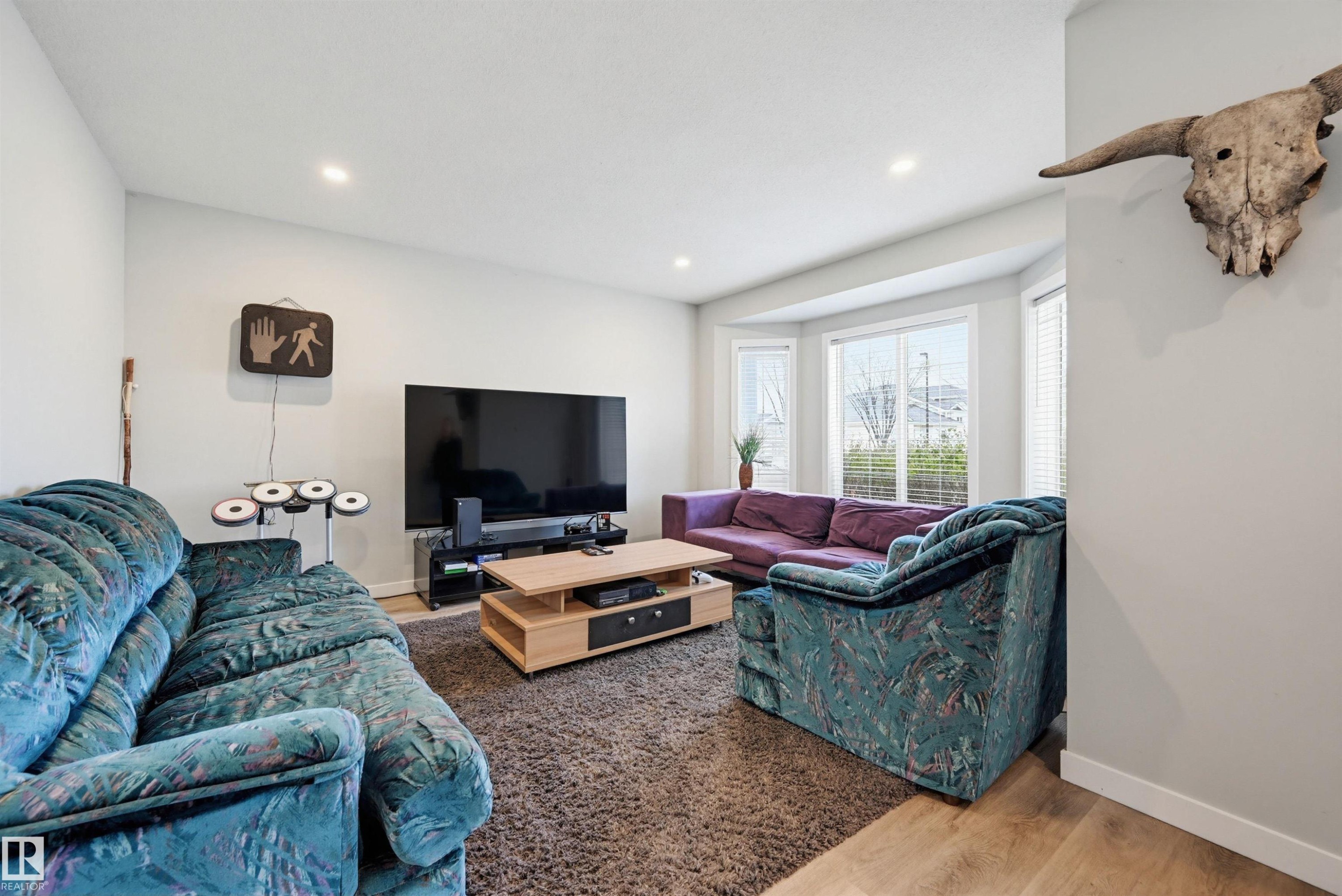 Spacious living area featuring light-toned walls, recessed lighting, and wood-finish flooring - 11 3380 28A Avenue Nw, Edmonton, AB - Indoor Photo Showing Living Room