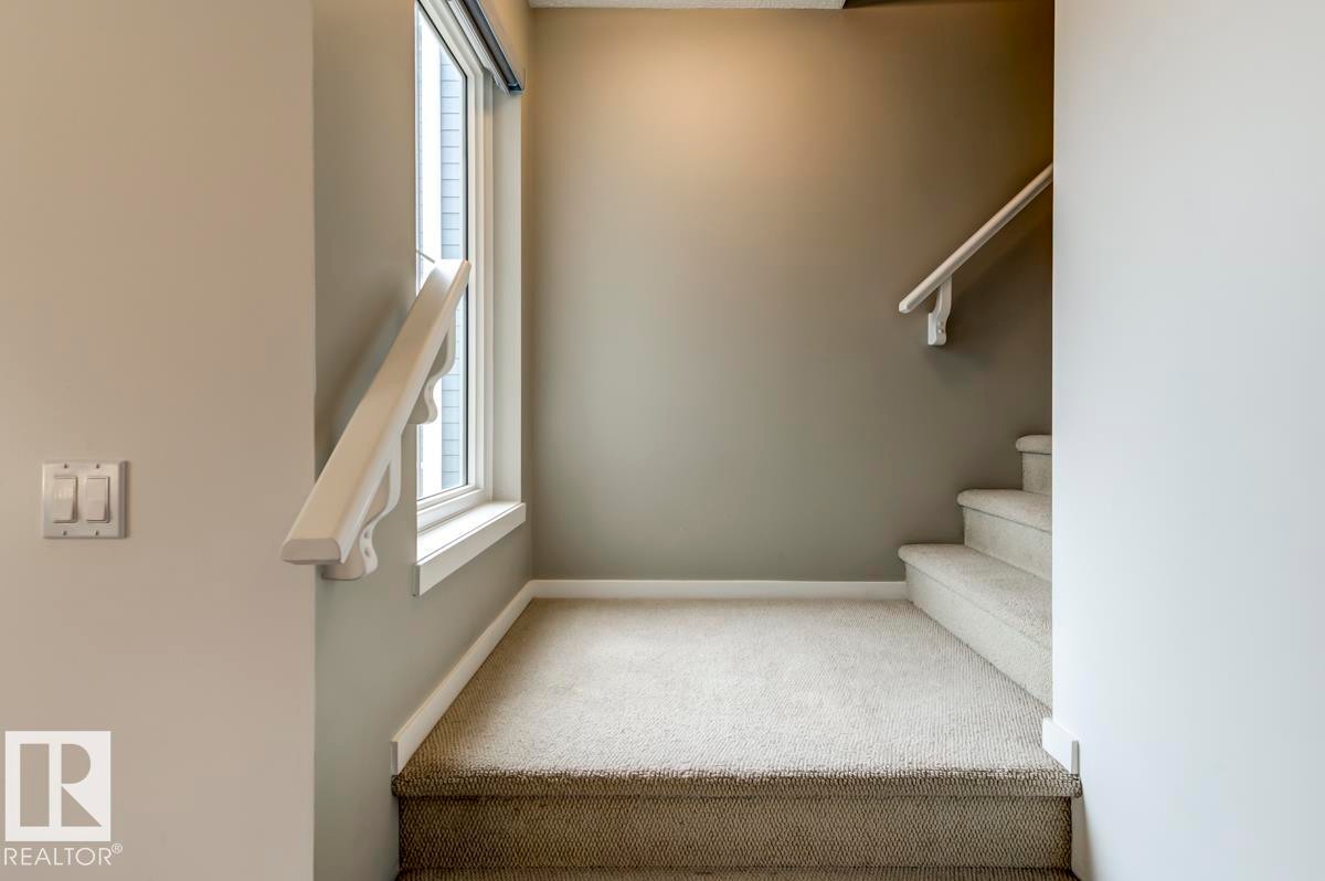 Carpeted staircase featuring a window and painted handrail - 67 603 Watt Boulevard, Edmonton, AB - Indoor Photo Showing Other Room