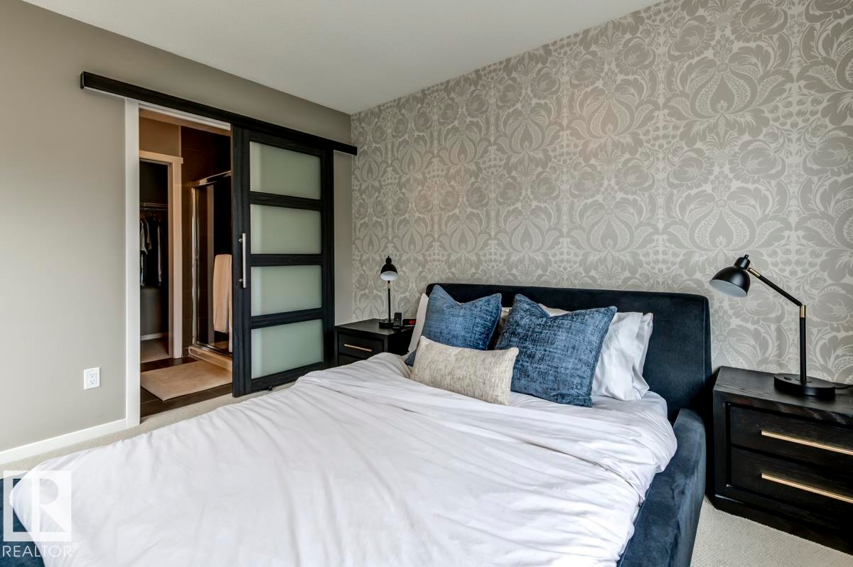Bedroom featuring patterned wallpaper, neutral wall tones, and carpet flooring - 67 603 Watt Boulevard, Edmonton, AB - Indoor Photo Showing Bedroom