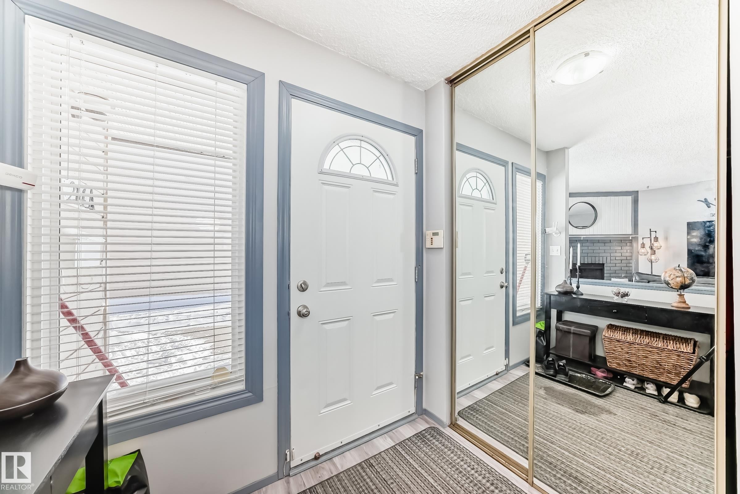 Entryway featuring light wood-finish flooring, a white door with an arched glass insert, and a window with white horizontal blinds - 214A Warwick Road, Edmonton, AB - Indoor Photo Showing Other Room