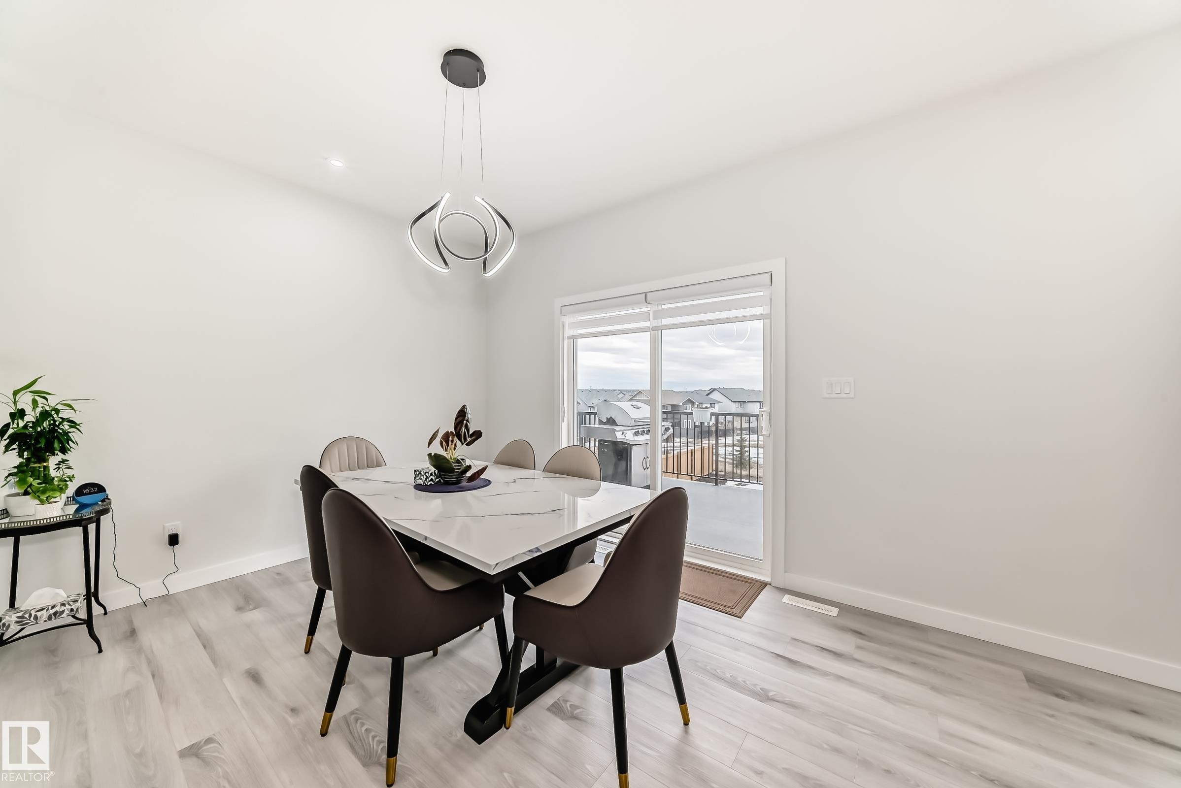 This dining area features light-colored flooring, a modern light fixture, and a sliding glass door providing access to the outdoors - 4509 170A Avenue, Edmonton, AB - Indoor Photo Showing Dining Room